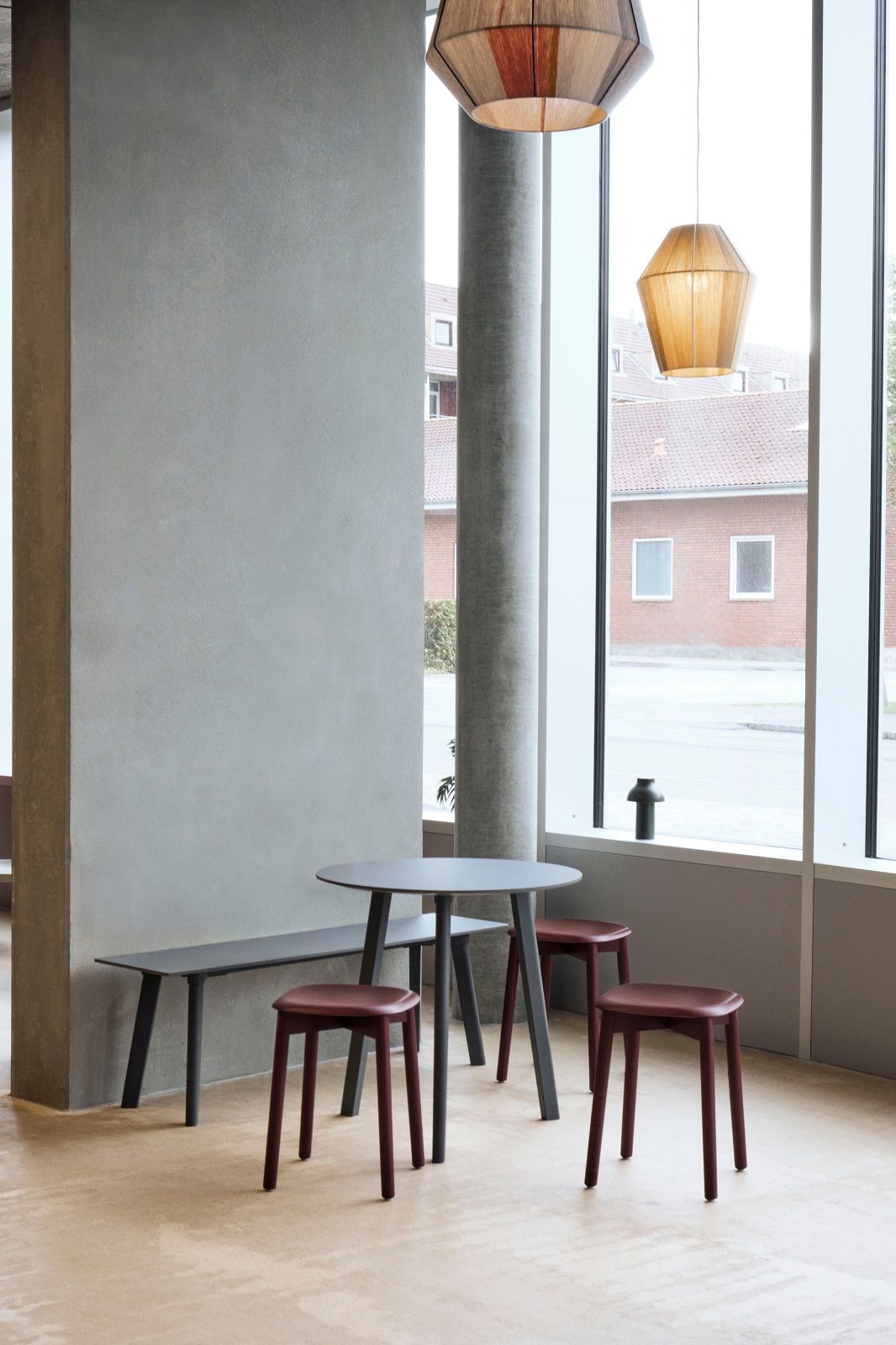 Innenaufnahme mit drei Soft Edge Hockern von Hay in Burgunderrot, Tisch und Sitzbank.