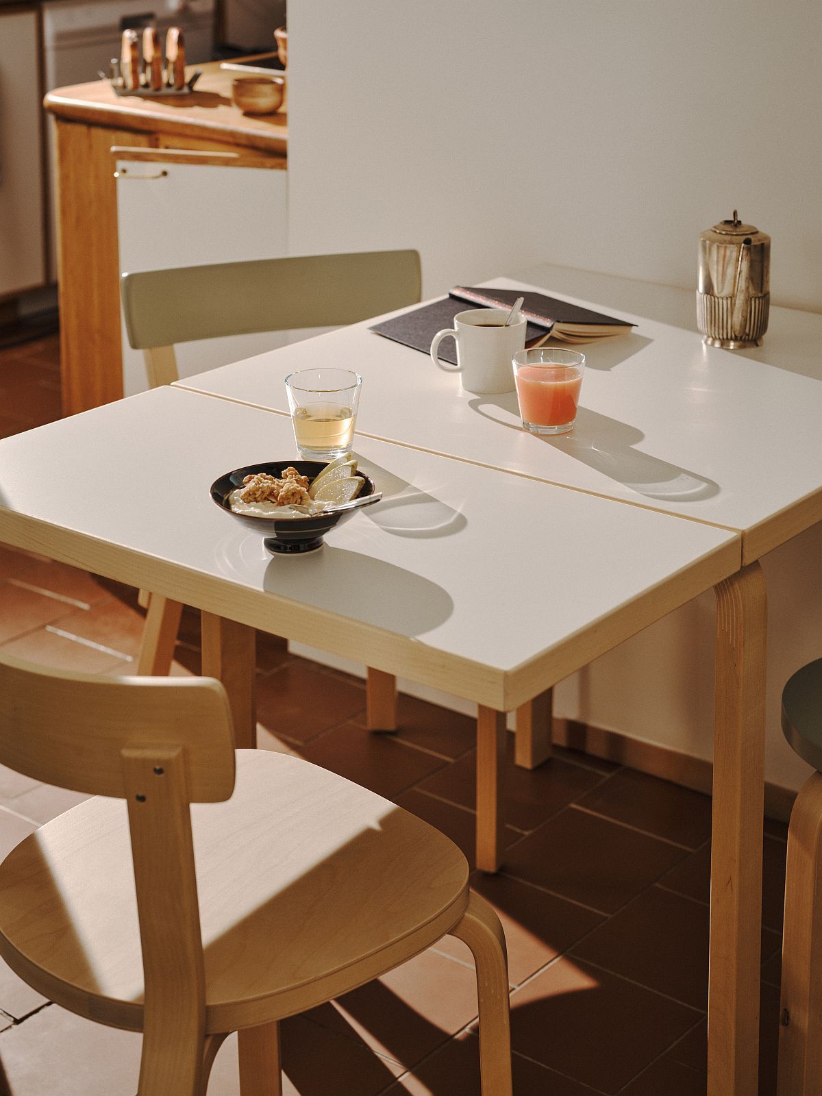 Aalto Table von Artek, ein weißer Klapptisch aus Holz mit Speisen und Getränken.