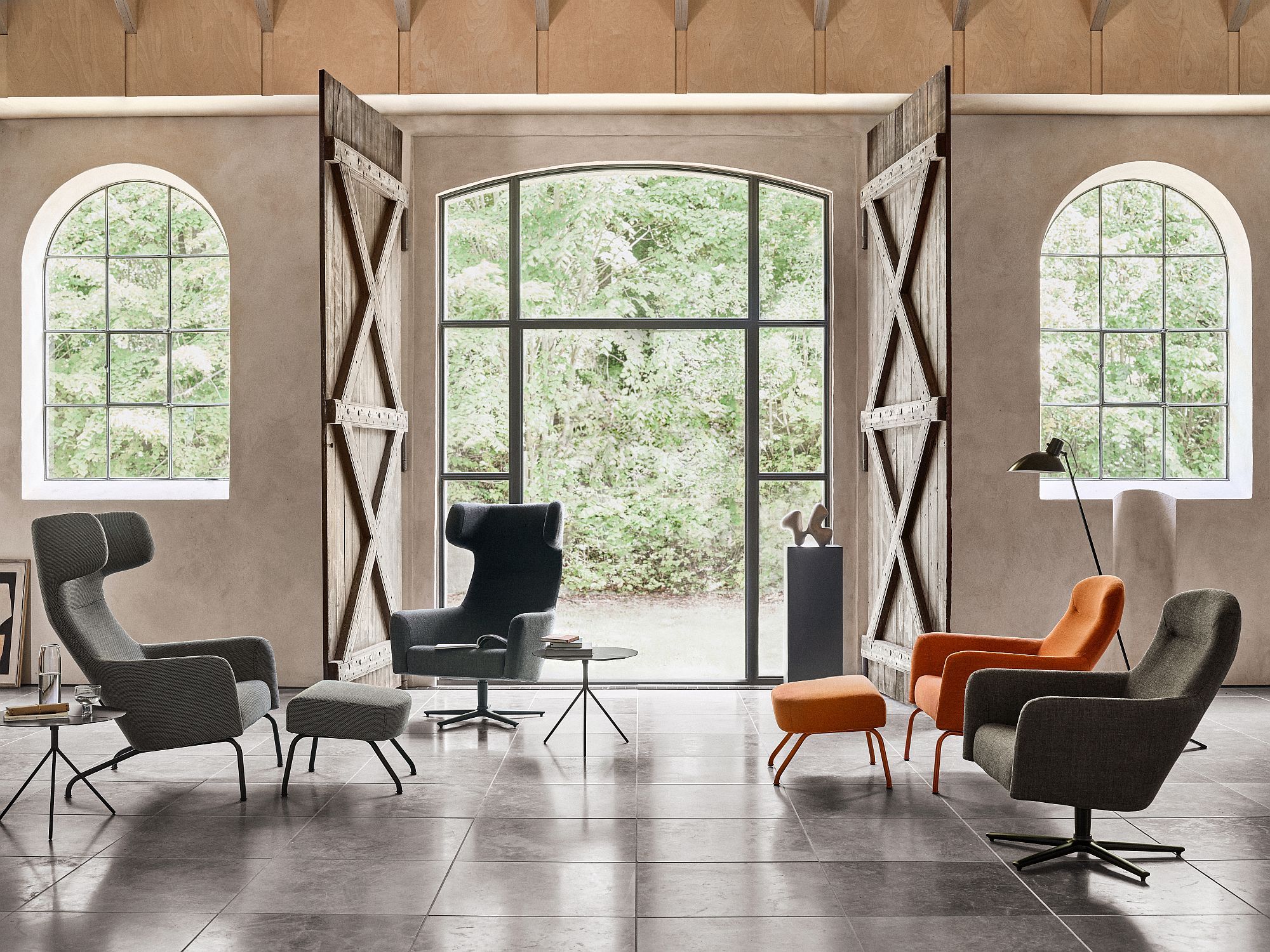 Innenaufnahme mit verschiedenen Sesseln und dem Havana Fußhocker Softline in Orange.