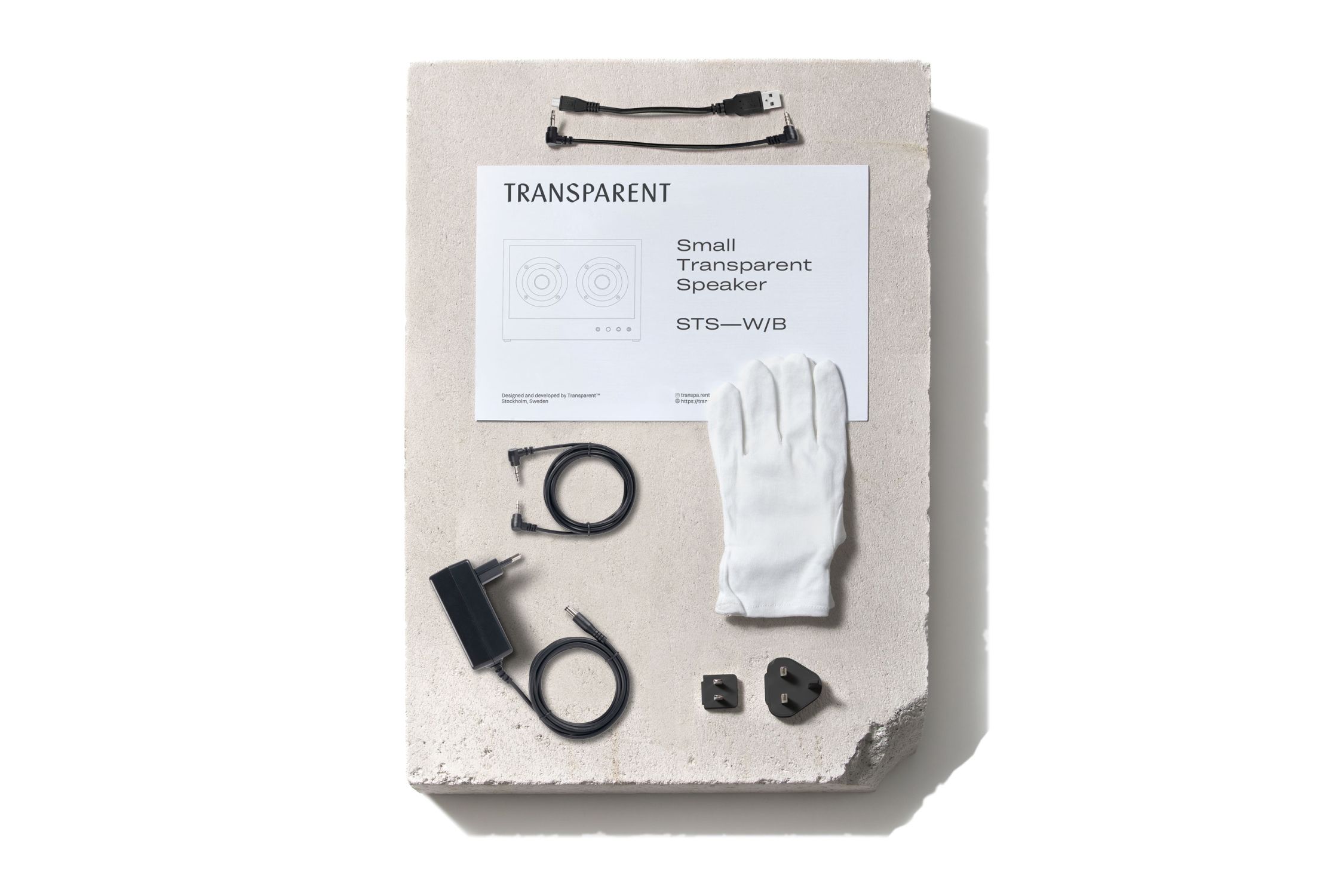 Produktbild: Kleiner Transparent Lautsprecher mit Zubehör wie Kabel, Netzteil und Handschuh.