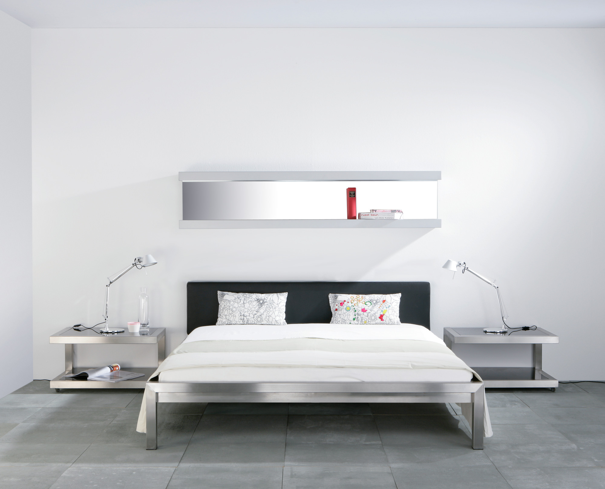 Hans Hansen Pure Bett: Edelstahlbett 160x200 mit schwarzem Polsterkopfteil und passenden Nachttischen.