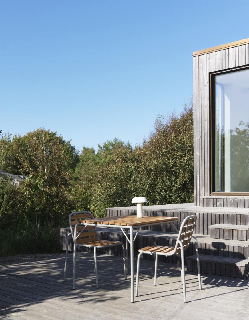 Nahaufnahme von zwei Vig Chair Wood Stühlen von Normann Copenhagen und einem Holztisch im Freien.