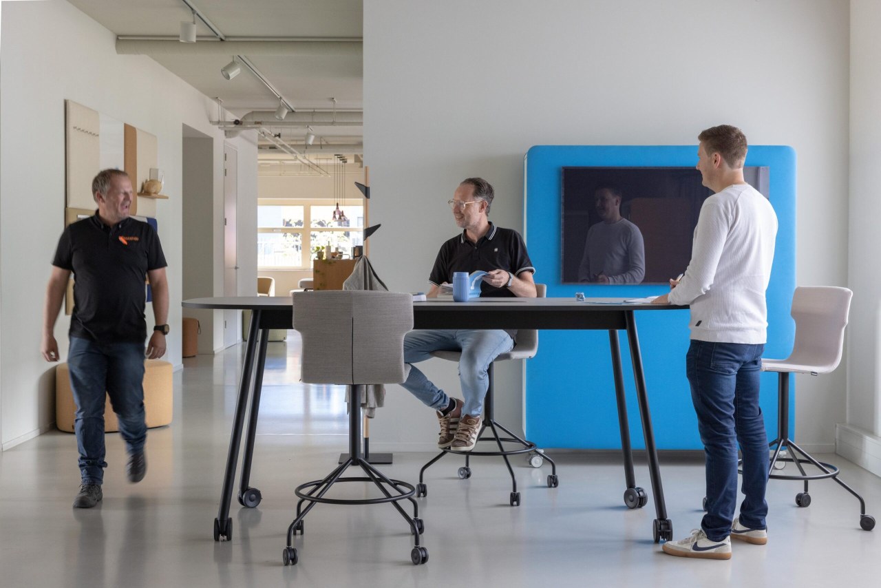 Co-Chair Bürodrehstuhl Cascando in modernem Büro mit drei Personen an einem höhenverstellbaren Tisch.