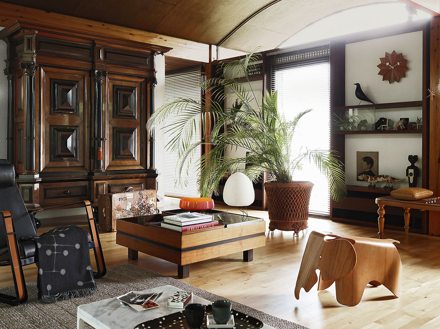 Innenaufnahme eines Wohnzimmers mit Vitra CitÉ Sessel, Holzschrank, Holztisch und Dekorationen.
