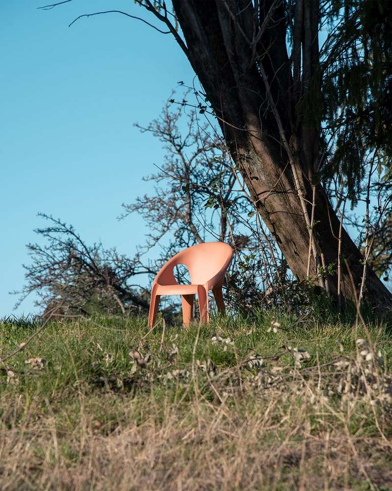 Pfirsichfarbener Bell Chair von Magis, ein moderner Outdoor-Stuhl mit Armlehnen, stapelbar, im Garten.