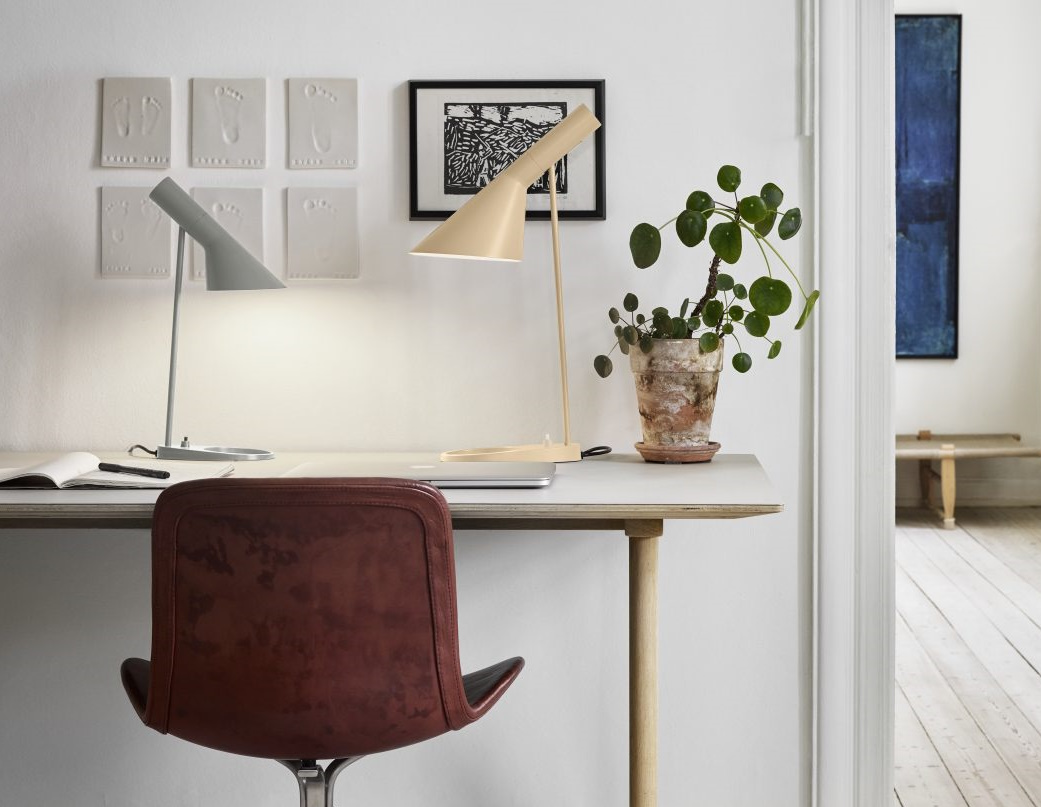 Zwei moderne Schreibtischlampen in Grau und Beige auf einem Schreibtisch mit Pflanze und Lederstuhl.