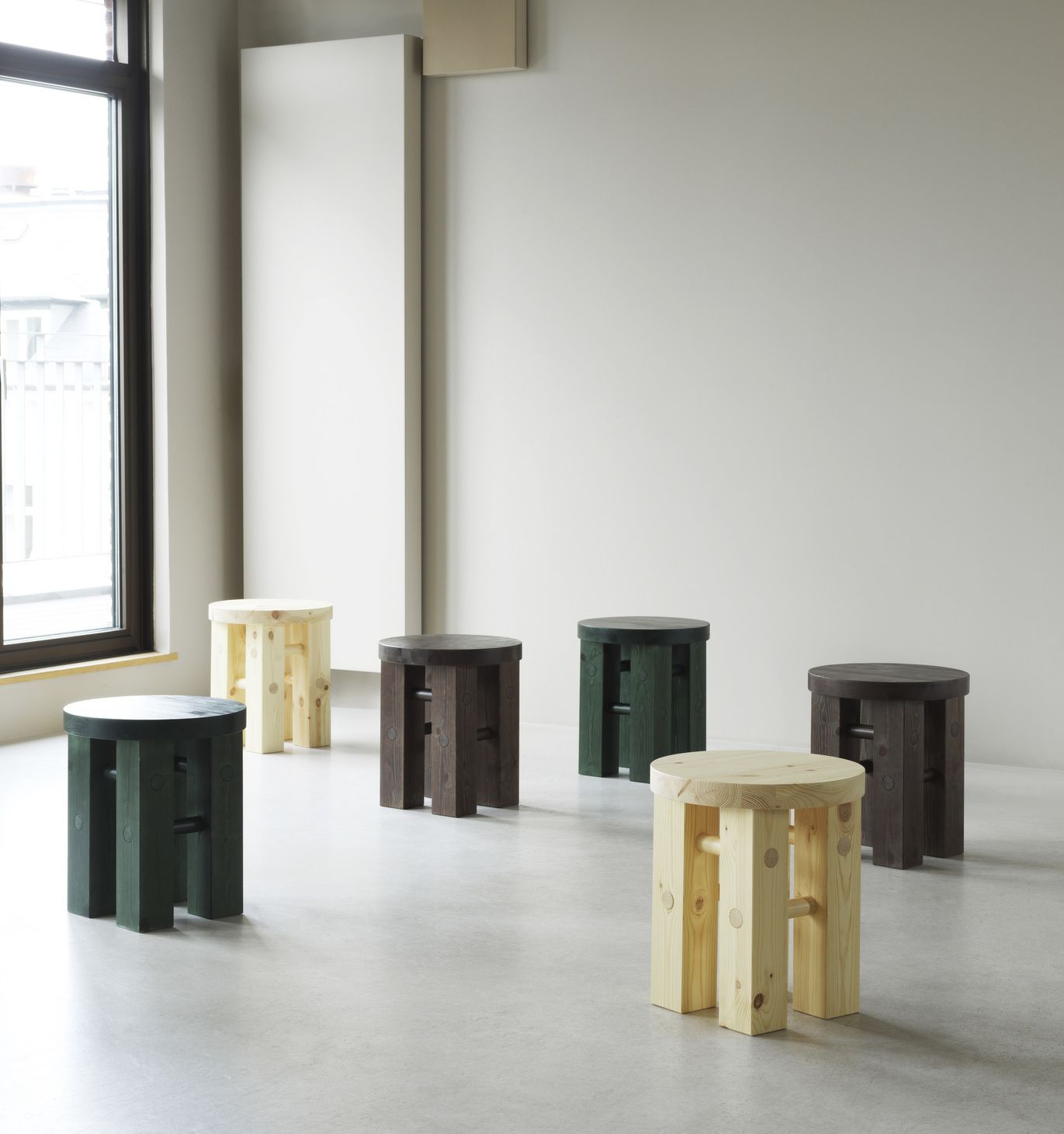 Verschiedenfarbige Fyr Stool Hocker von Normann Copenhagen aus Holz stehen in einem hellen Raum.