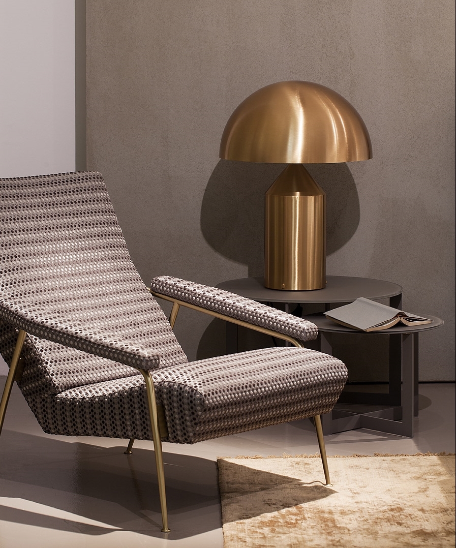 Goldene Atollo Tischleuchte von Oluce auf einem Beistelltisch neben einem Sessel. Design Lampe.