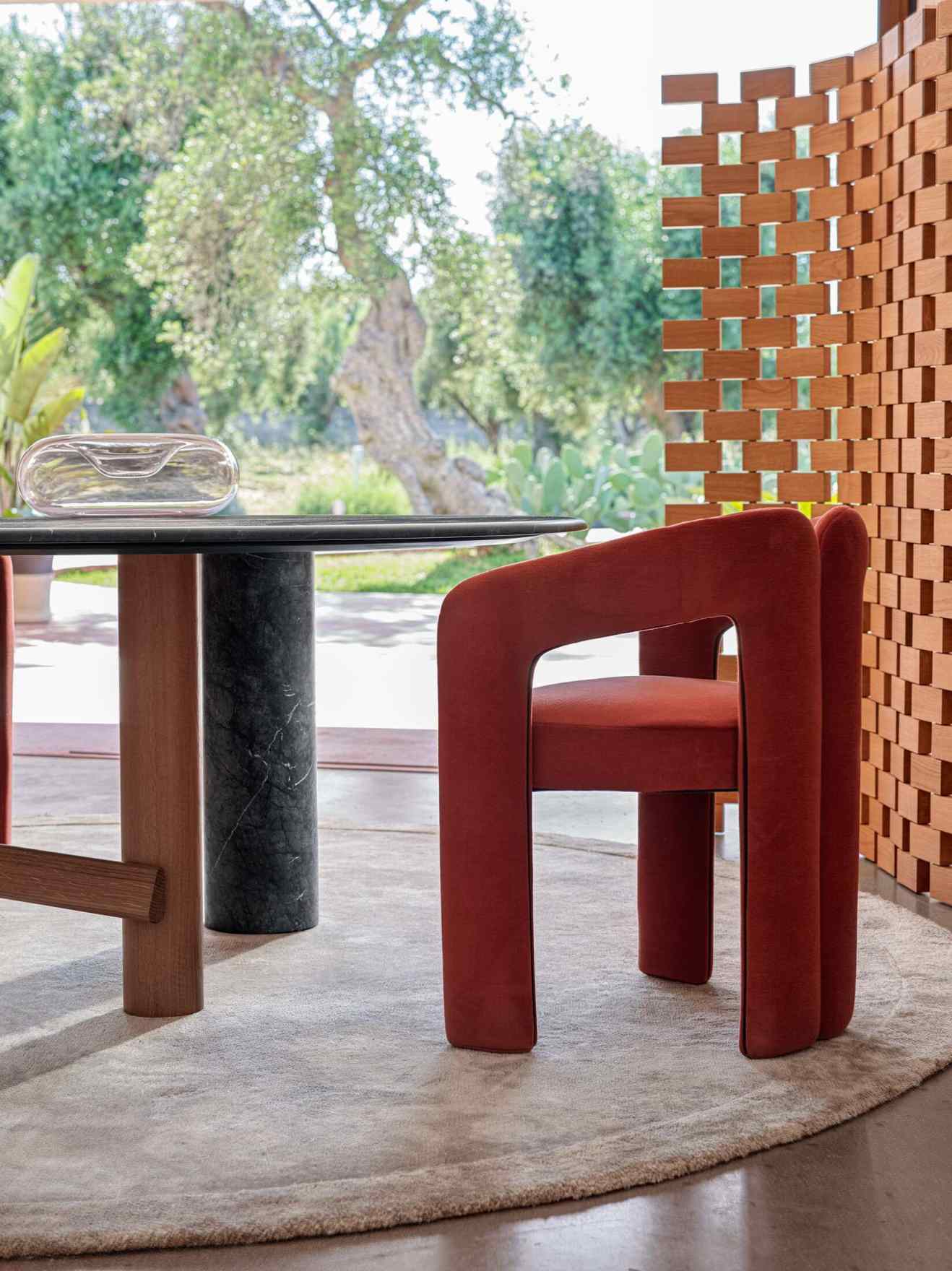 Nahaufnahme des Cassina 562 Dudet Sessels in Terrakotta-Rot mit abgerundeten Formen und minimalistischem Design.