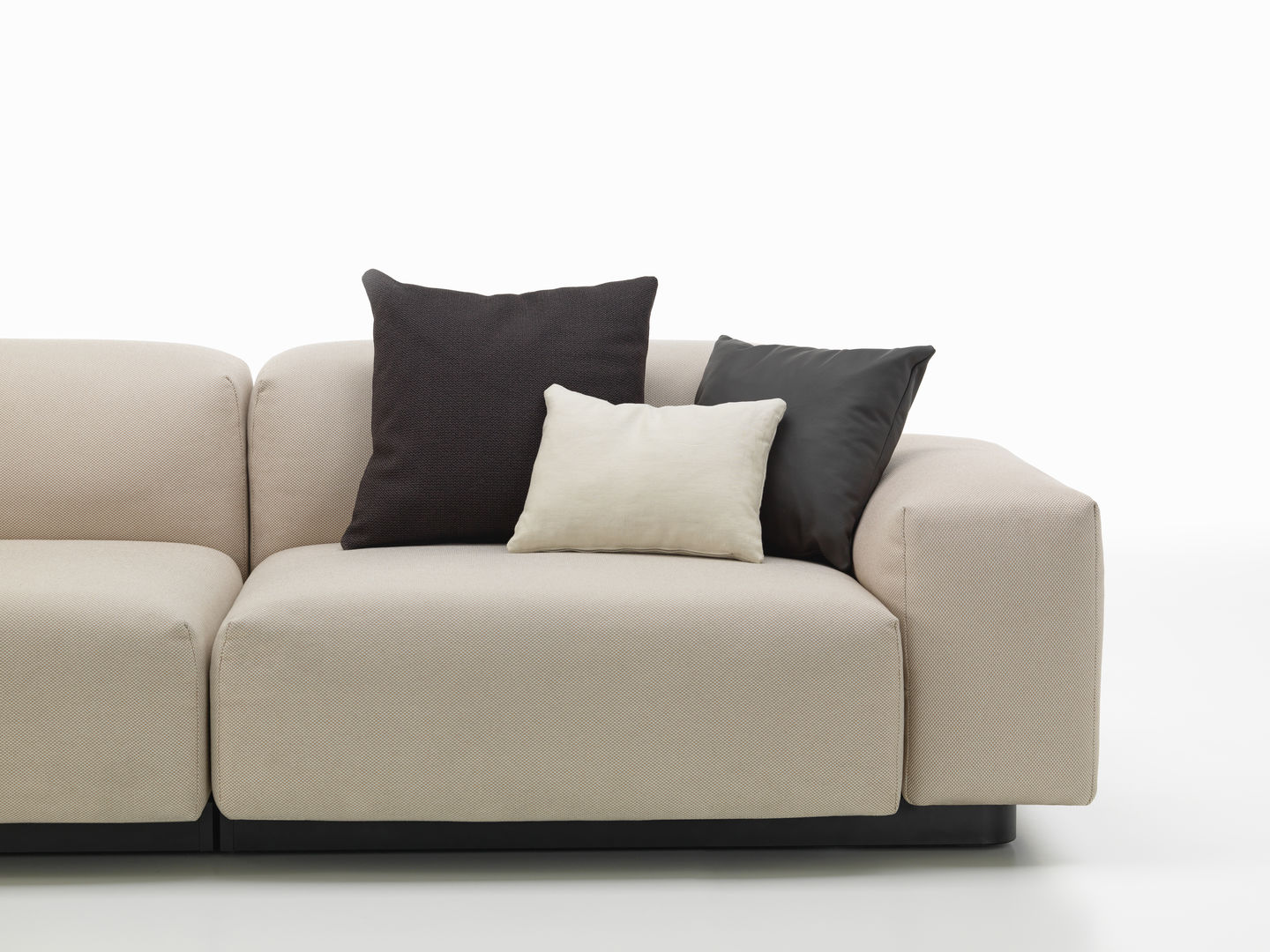 Nahaufnahme eines beigen Sofas mit drei Vitra Kissen in Schwarz, Grau und Creme.