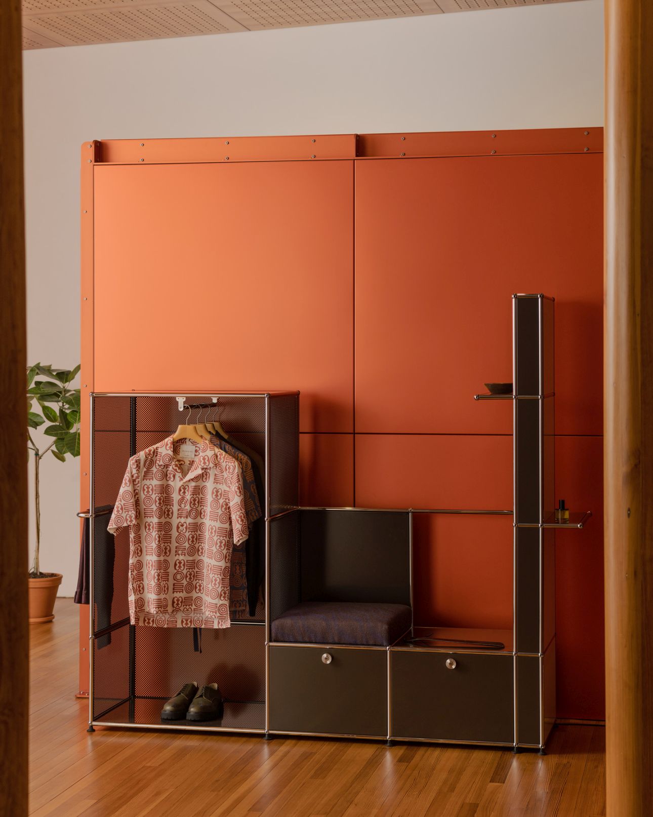 USM Haller Garderobe Okinka von Armando Cabral in Terrakotta mit Kleiderbügel, Sitzbank und Ablagefächern.