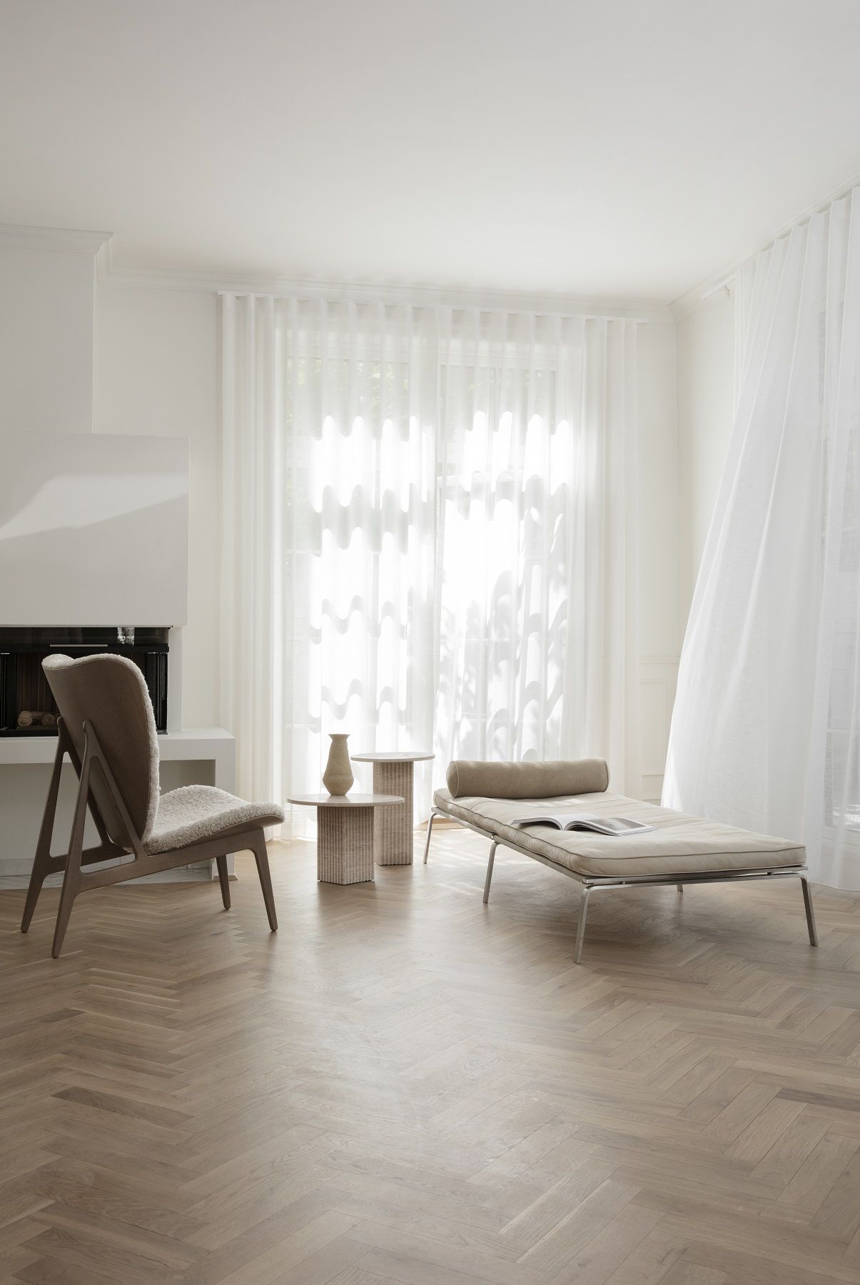 Heller Wohnraum mit NORR11 Elephant Lounge Chair Sessel, Liege und Beistelltischen auf Parkettboden.