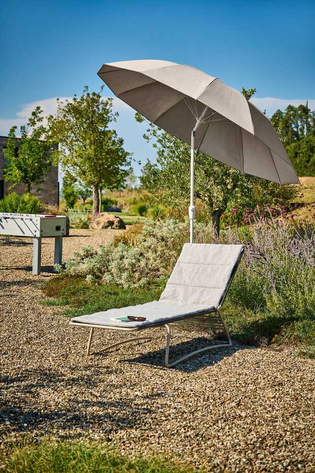 Weishäupl Pagodenschirm spendet Schatten über einer grauen Sonnenliege im Garten, ideal für entspannte Sommertage.