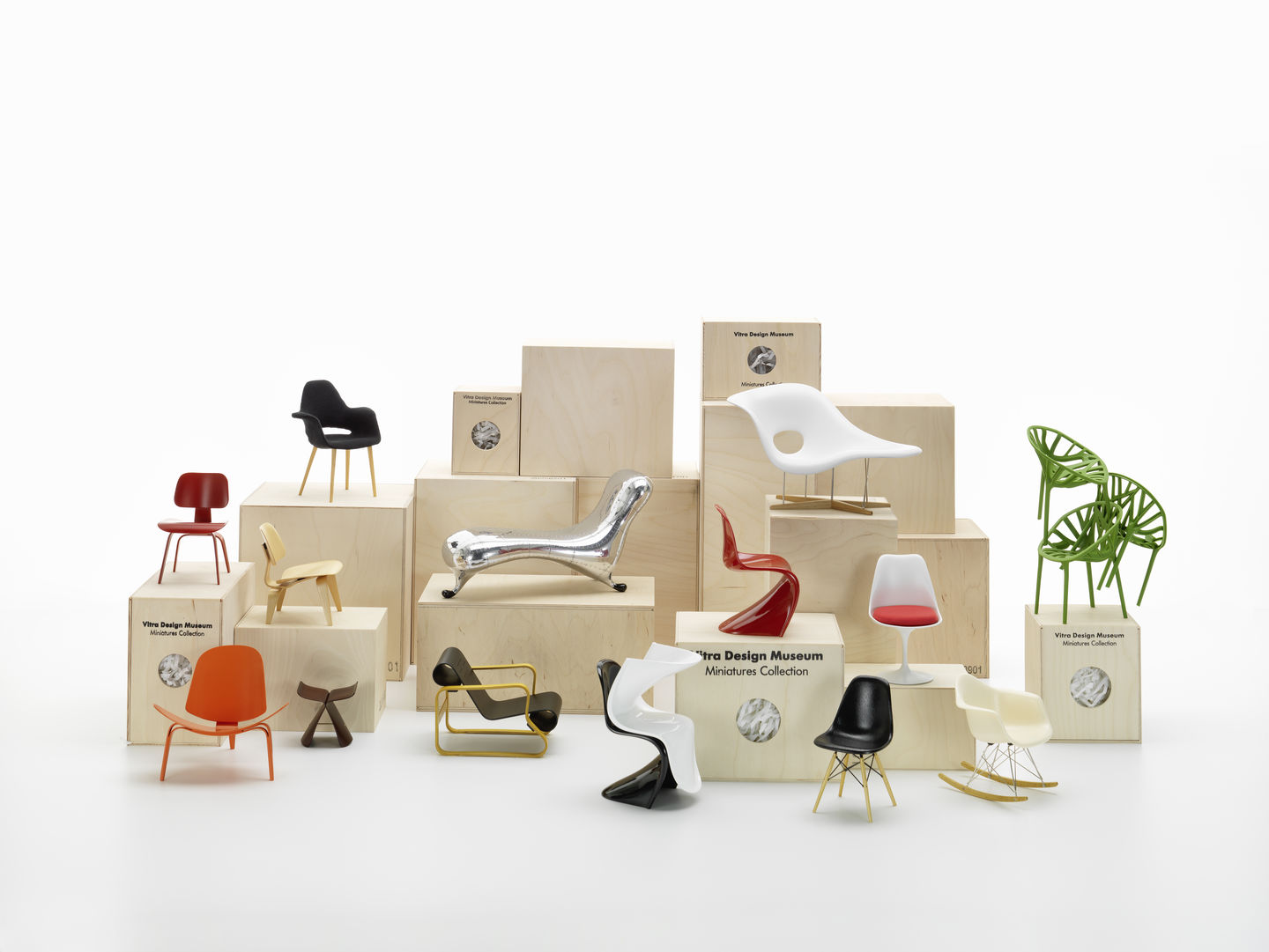 Vielfalt an Miniatur-Designstühlen der Vitra Design Museum Miniatures Collection auf Holzpodesten, verschiedene Farben und Stile.