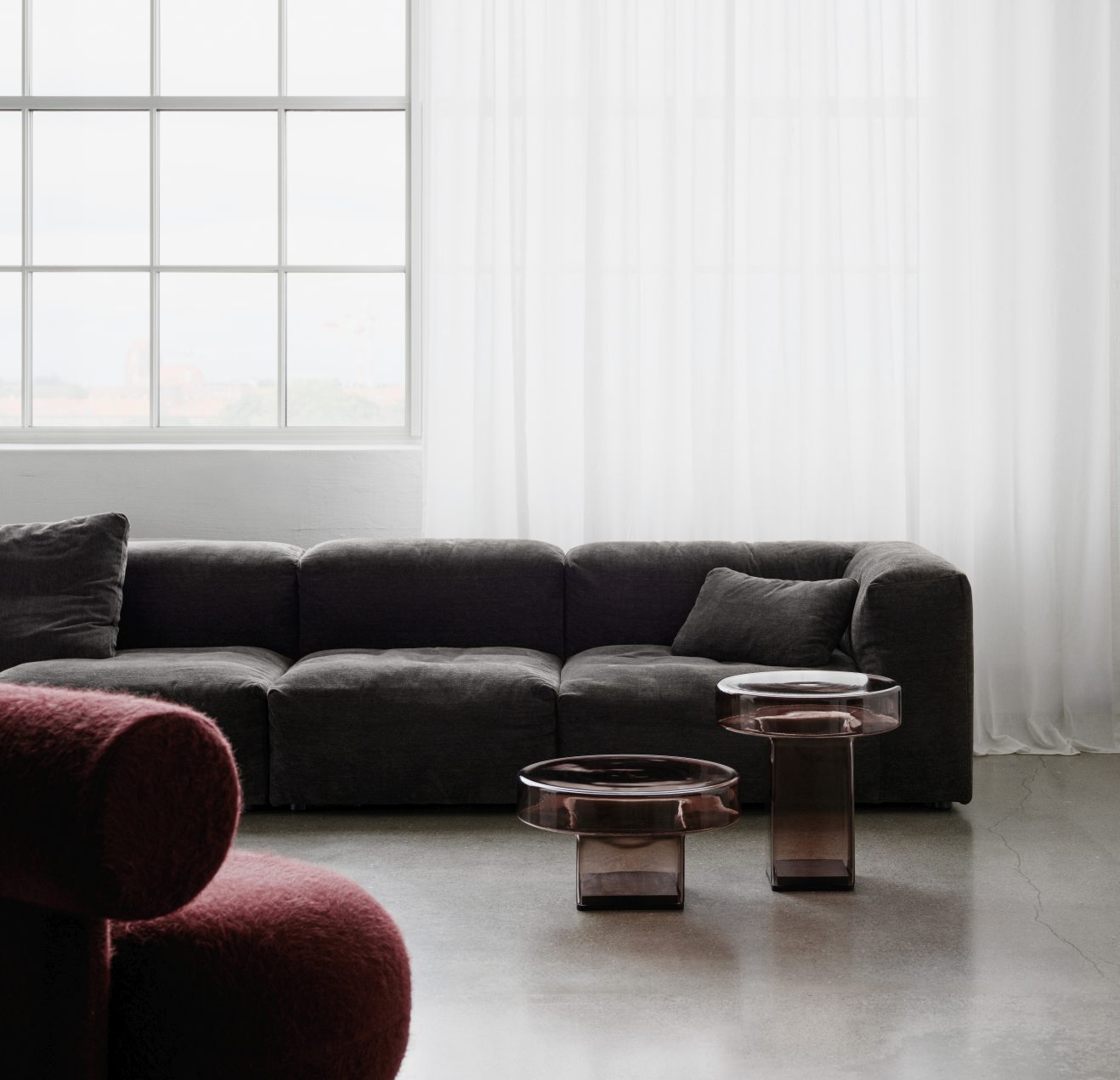Hippo Lounge Chair Sessel von NORR11, vollgepolstert in Rot, mit Sofa und Glastischen im Wohnzimmer.