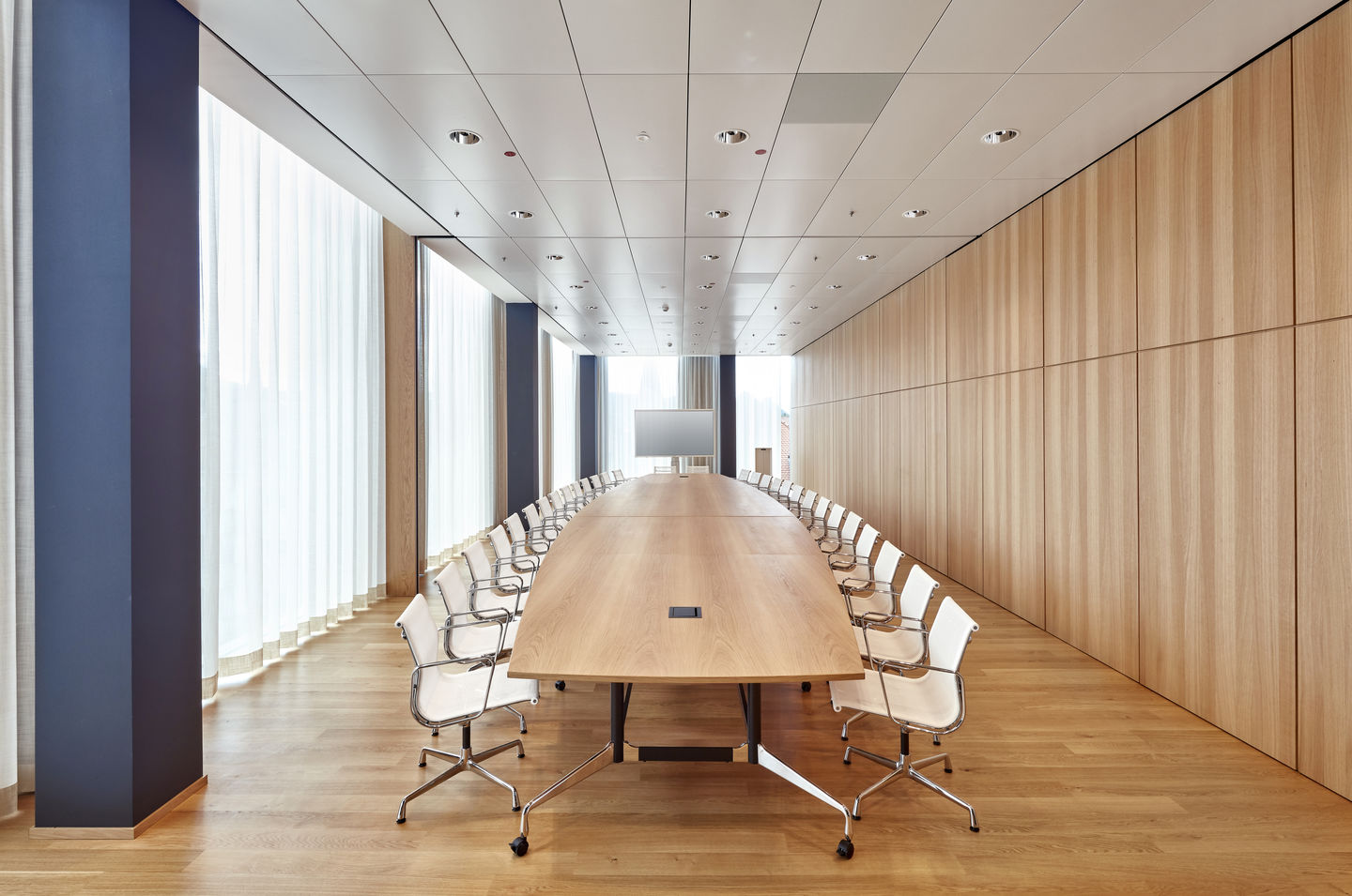 Konferenzraum mit langem Holztisch und weißen Aluminium Chair EA 104 Stühlen von Vitra.