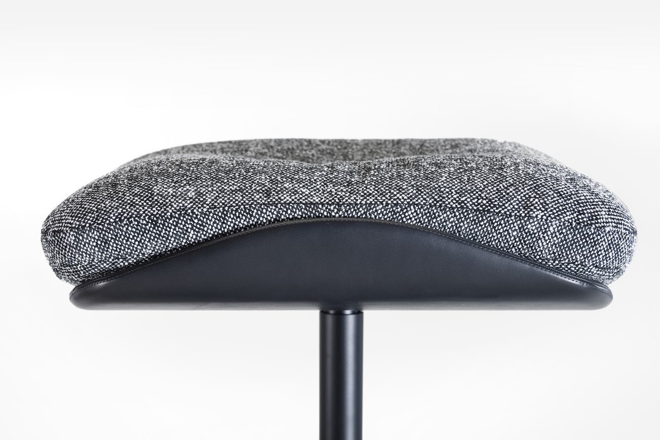 Detailaufnahme des Rei Hocker von Prostoria mit grau-weiß meliertem Stoffbezug und schwarzem Metallfuß.