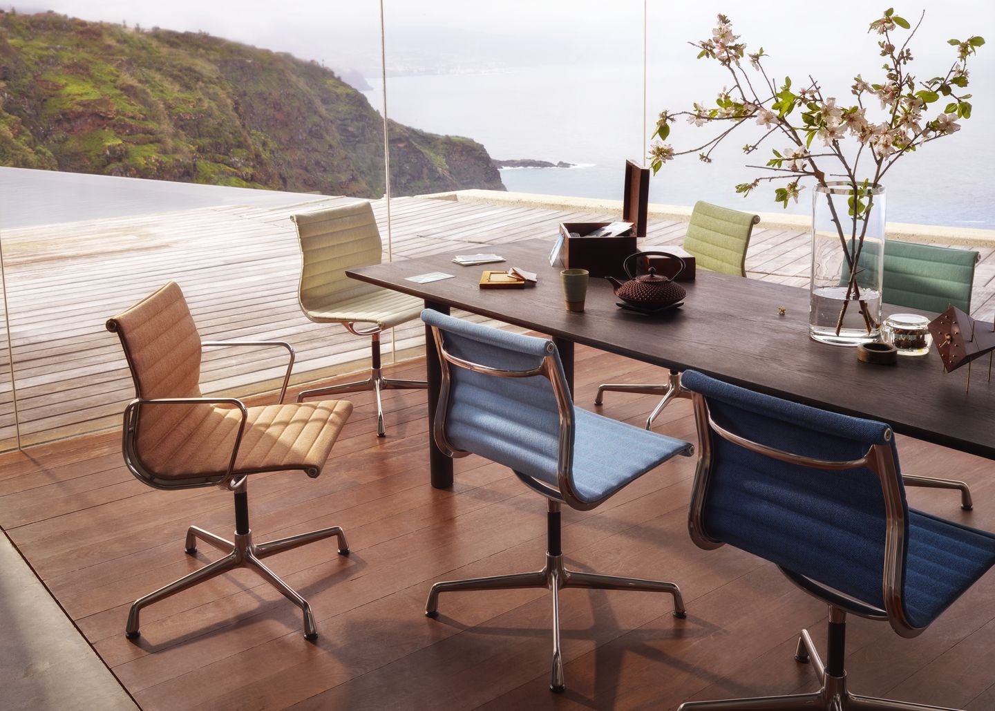 Aluminium Chair EA 101 von Vitra in verschiedenen Farben um einen dunklen Holztisch.
