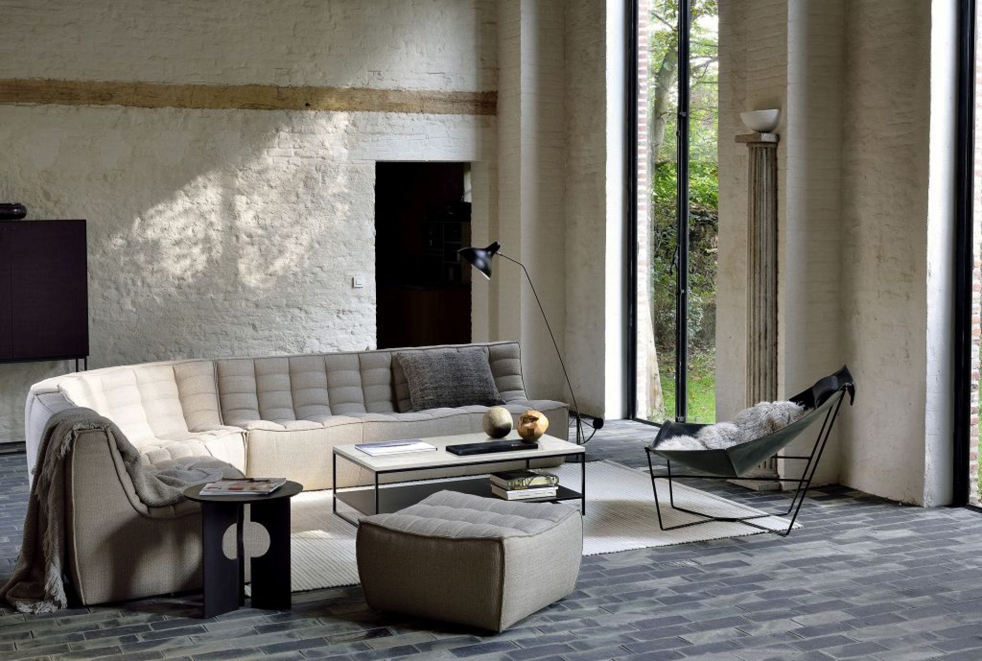 Helles Wohnzimmer mit modularem Sofa, Couchtisch, Sessel und Hocker in modernem Design.