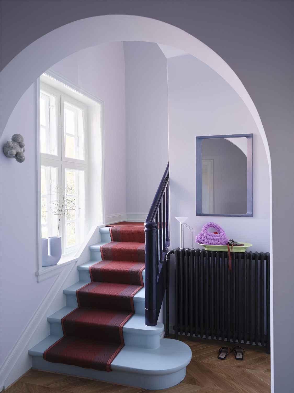 Arced Mirror Spiegel von Muuto im Flur über einem schwarzen Heizkörper mit Deko.