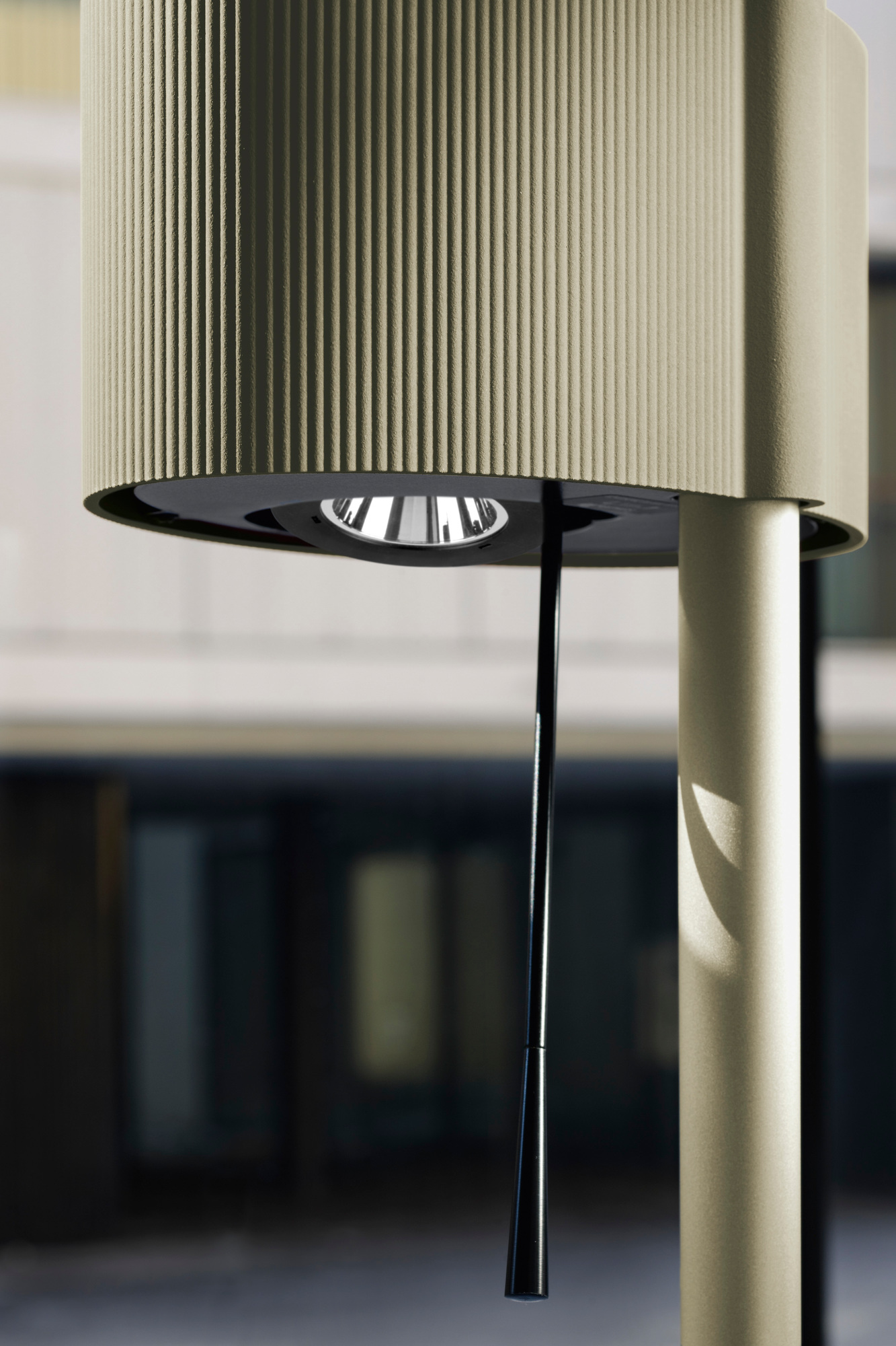 Detailaufnahme der Belux Diogenes LED Stehleuchte mit geripptem Lampenschirm und schwarzem Zugschalter vor Gebäude.