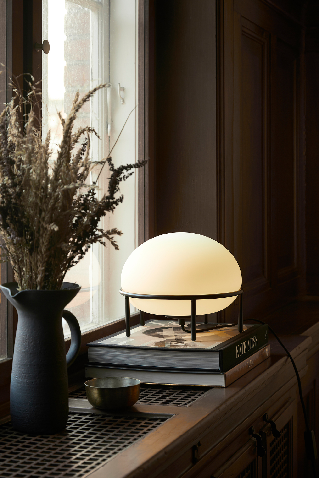 Nahaufnahme der Woud Pump Table Lamp Tischleuchte mit schwarzem Gestell und opalweißem Glasschirm.