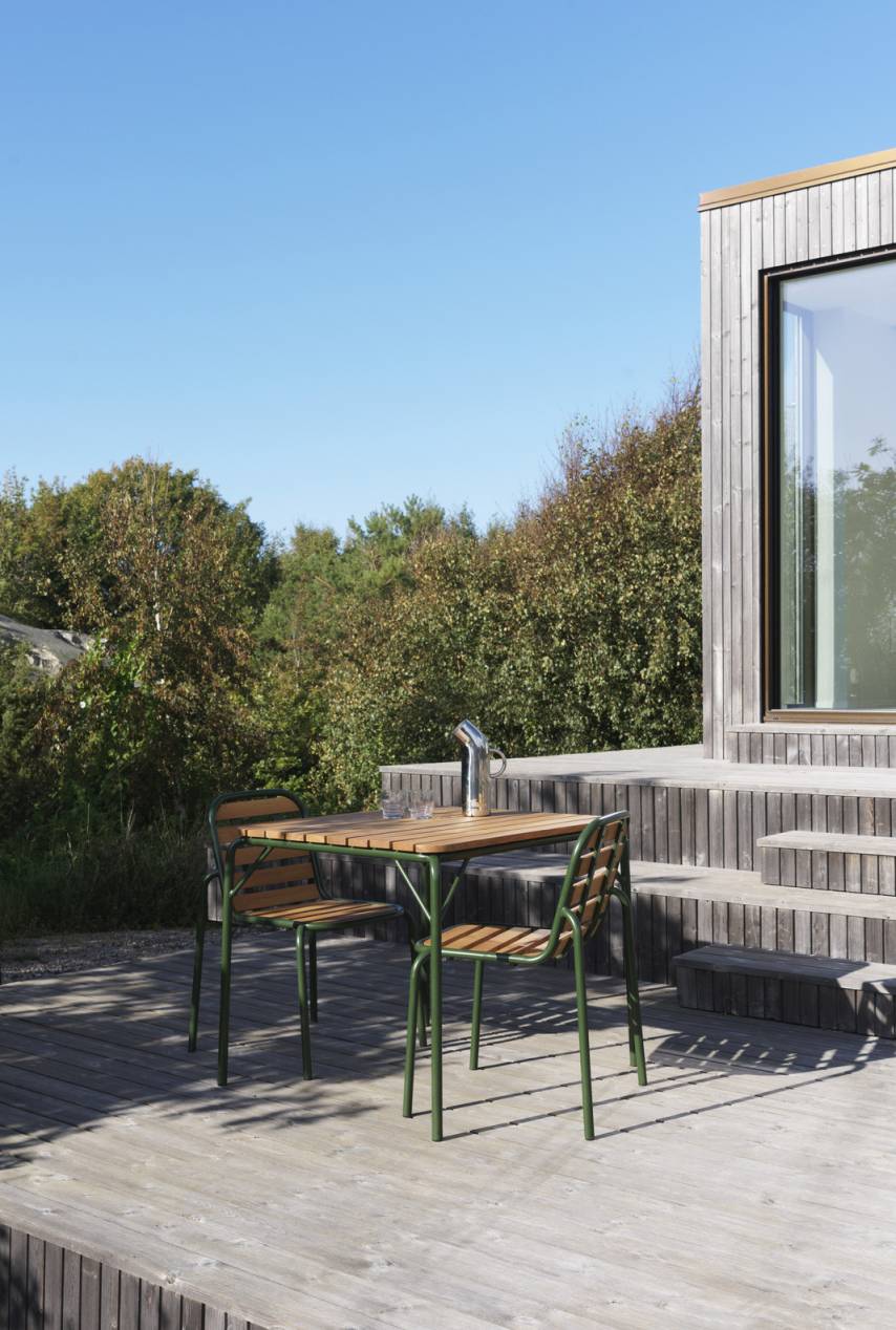 Normann Copenhagen Vig Chair Wood Stuhl Outdoor auf Holzterrasse mit Tisch und Wasserkanne.