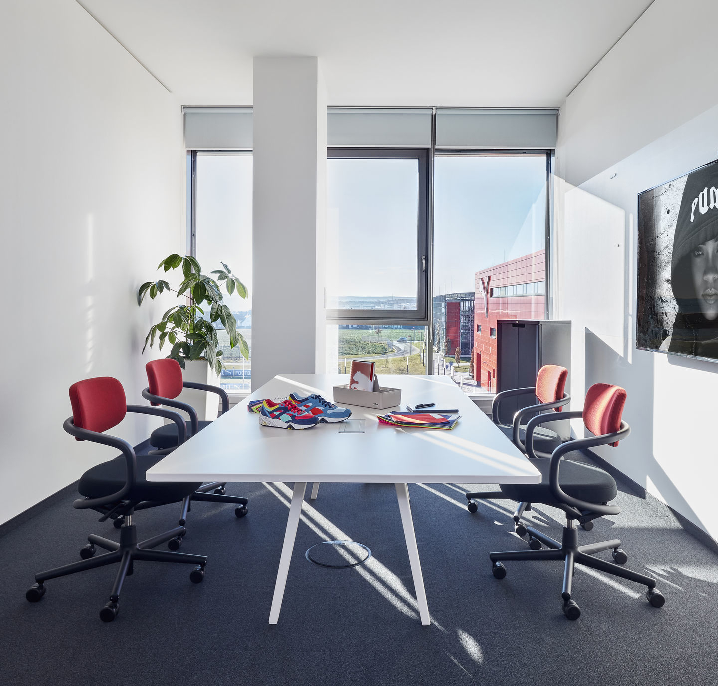 Konferenzraum mit vier Allstar Bürodrehstühlen von Vitra in Schwarz und Rot am weißen Tisch.