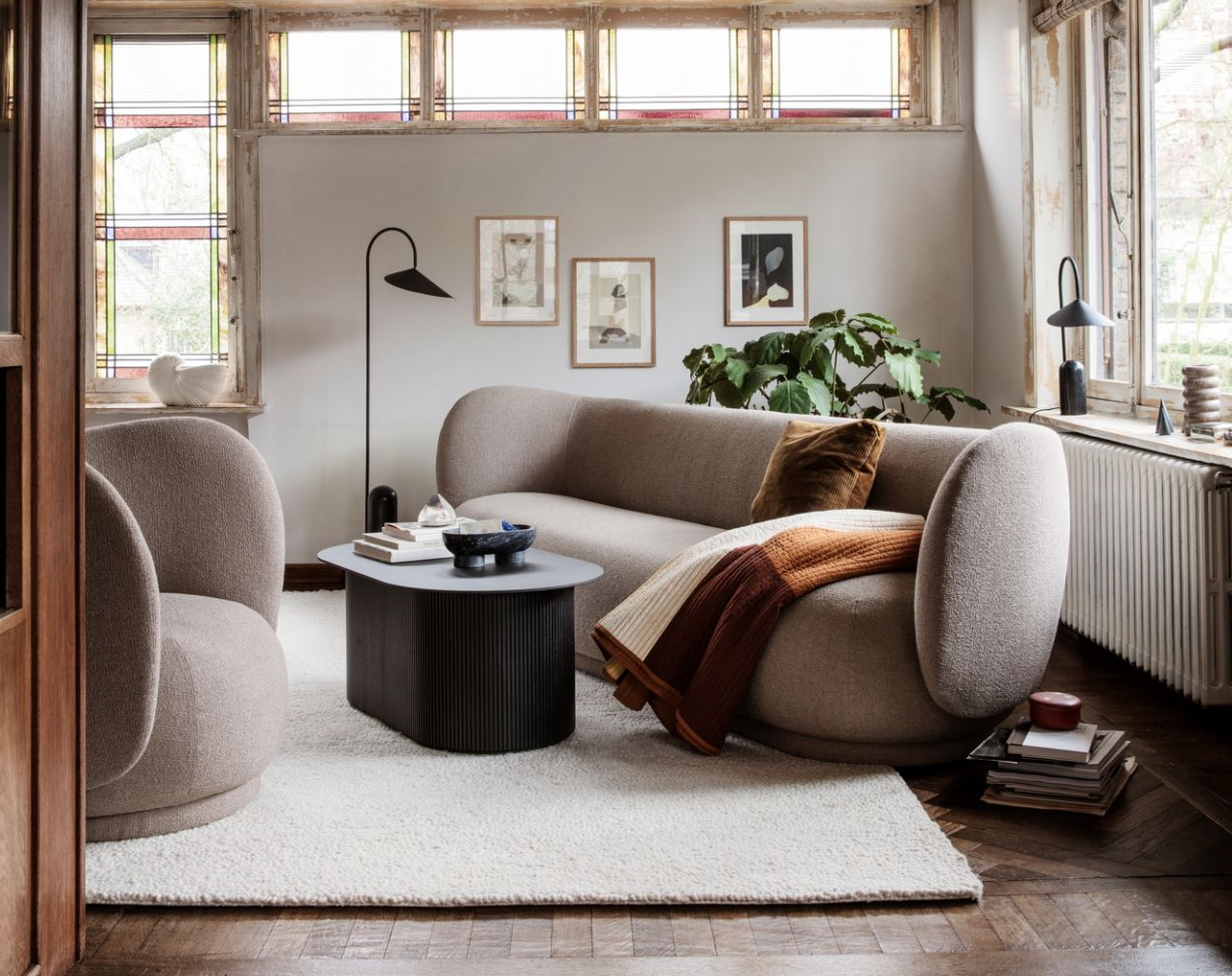 Wohnzimmer mit beigem Sofa, Sessel, schwarzem Couchtisch und weißem Teppich für gemütliches Wohnen.