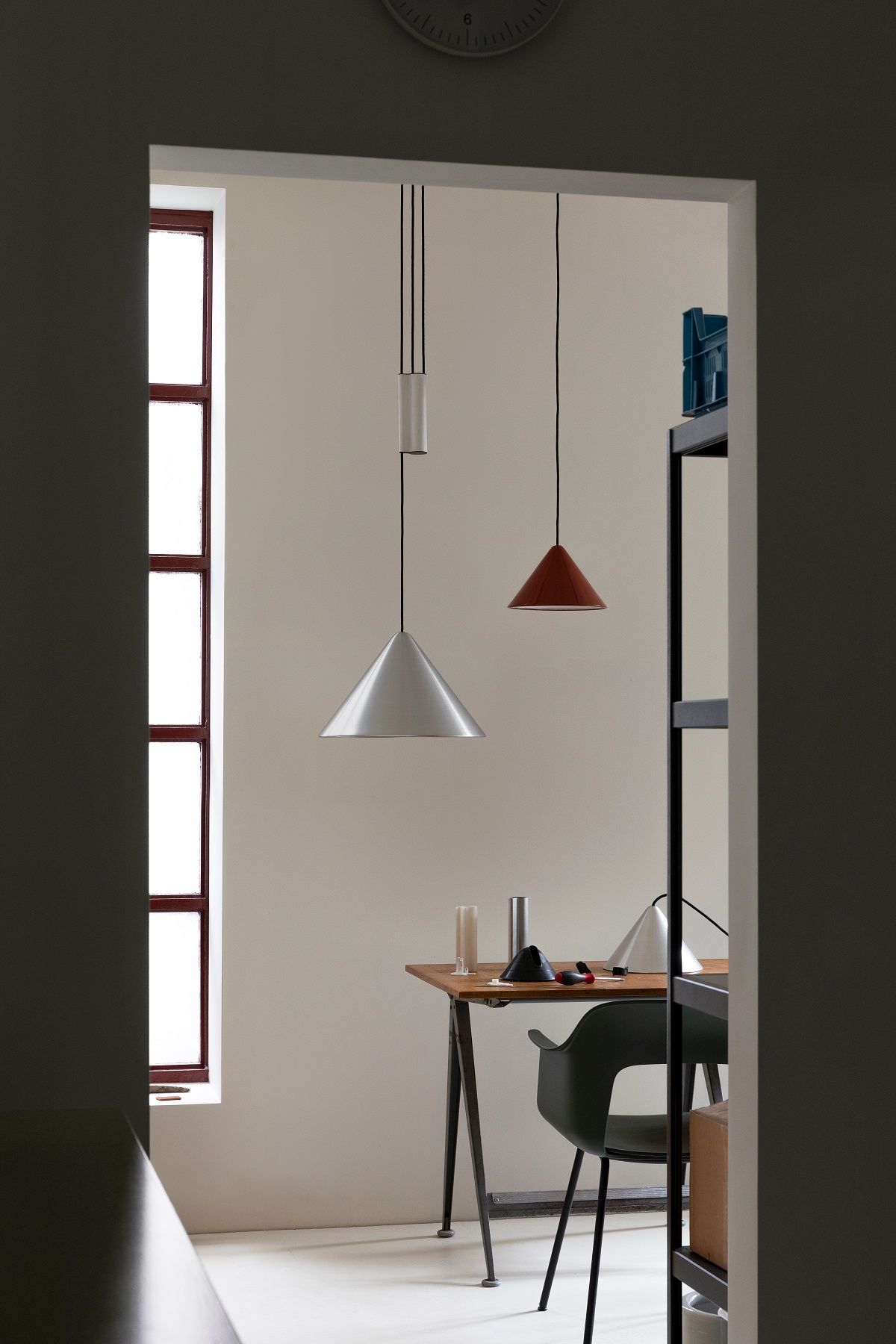 Compass Adjustable Pendelleuchte von Hay in Silber und Rot über einem Holztisch in einem modernen Raum.