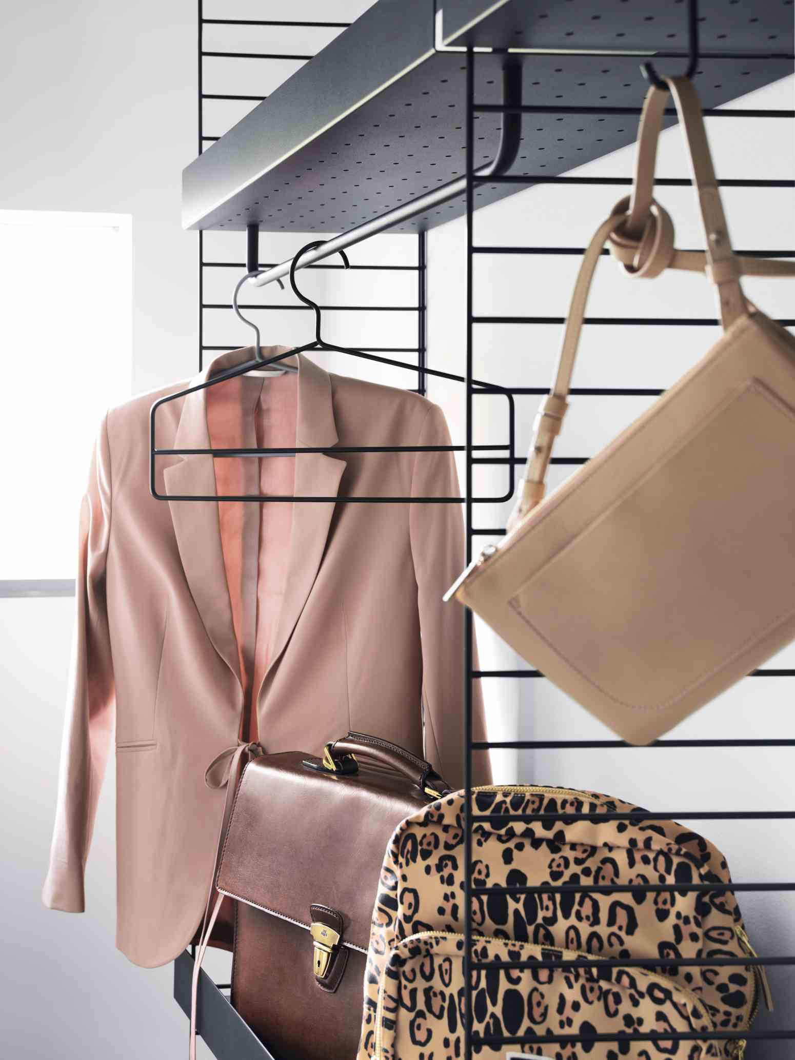 Schwarzes String Regalsystem mit Kleidung: Blazer, Aktentasche und Tasche. Vielseitige Wandregale für Schlafzimmer und mehr.