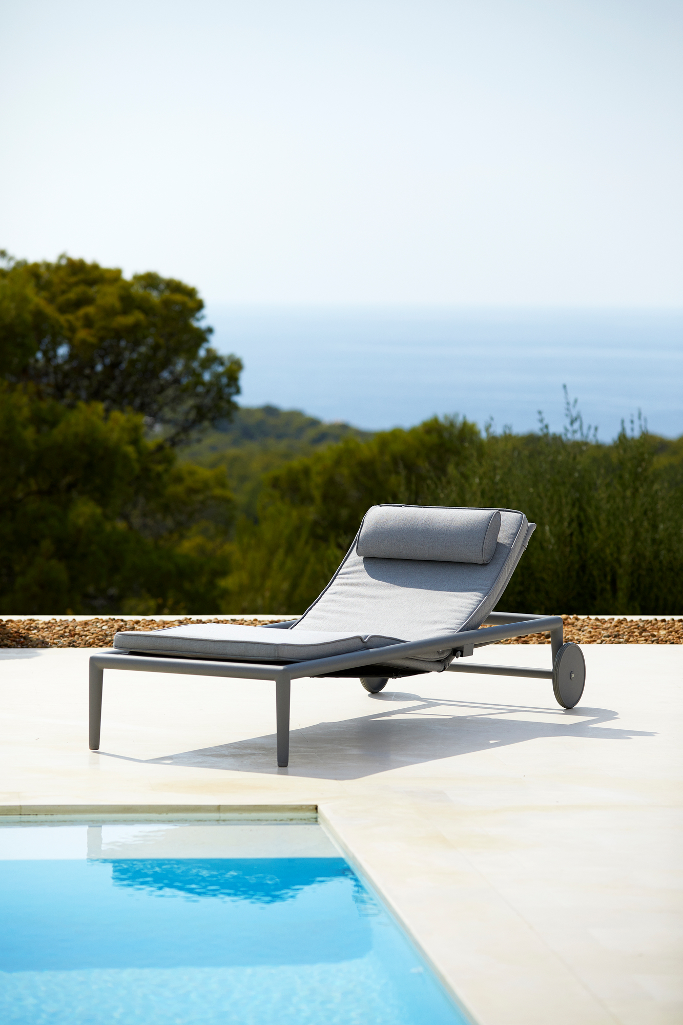 Graue Conic Sonnenliege von Cane-Line am Pool mit Blick auf das Meer. Outdoor Möbel.