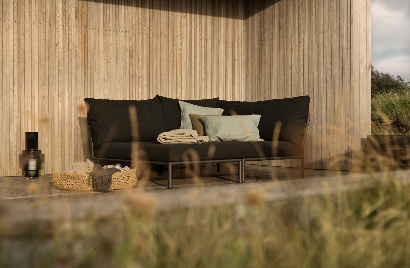 Level 2 Cozy Corner Sofa von Houe: Schwarzes Outdoor Ecksofa mit Kissen und Decke.