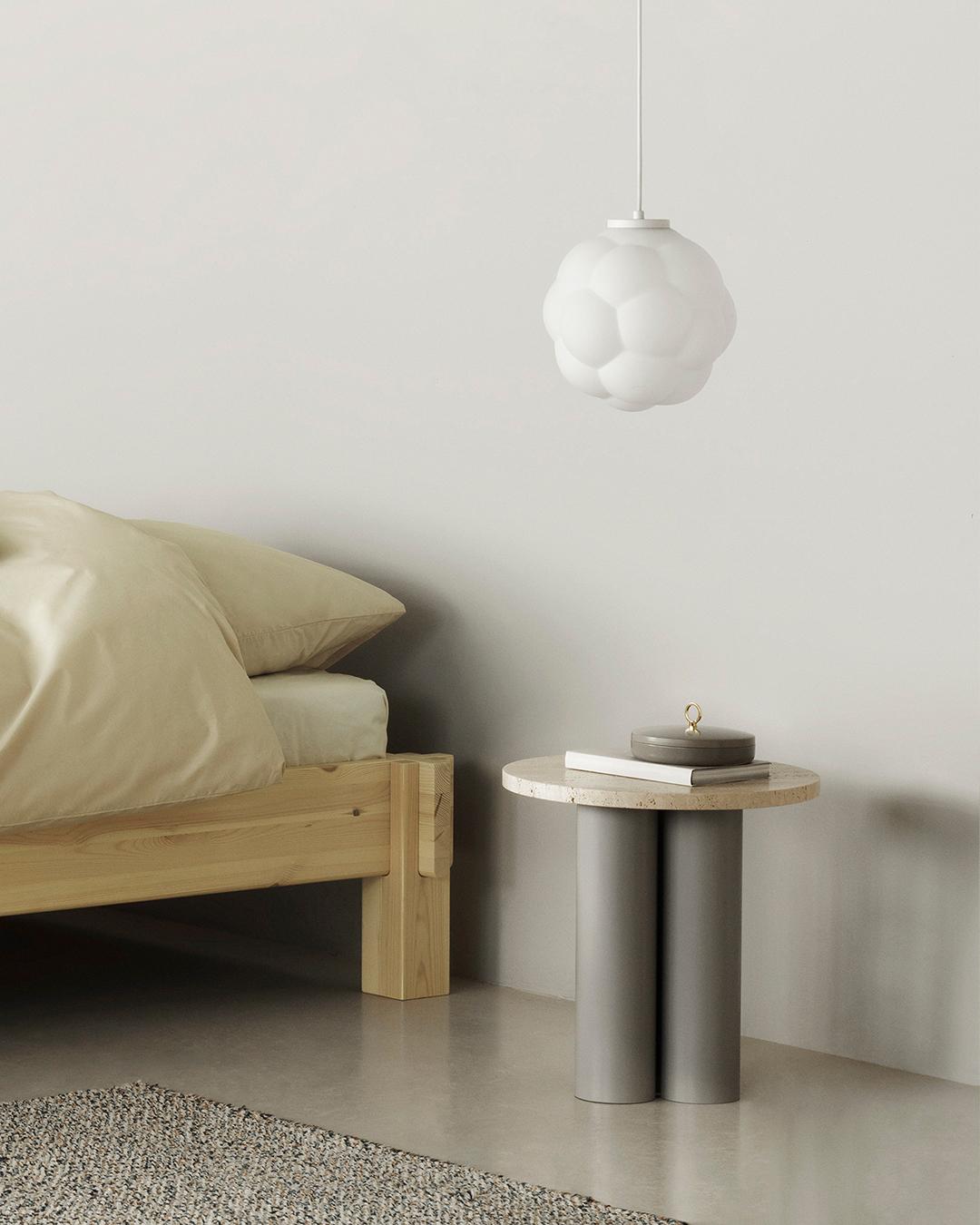 Normann Copenhagen Dit Coffee Table Beistelltisch im Schlafzimmer neben einem Holzbett und einer modernen Lampe.