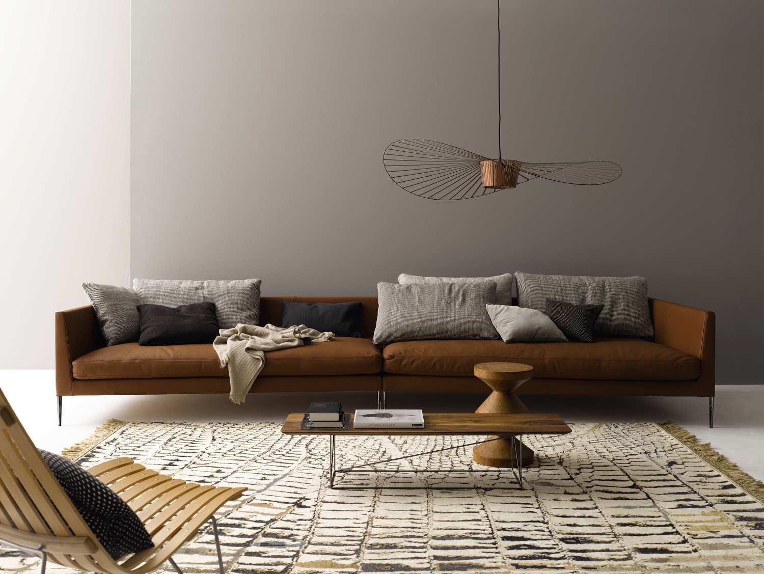 Braunes Cor Pilotis Sofa ohne Rückenkissen mit Dekokissen und Decke im Wohnzimmer.