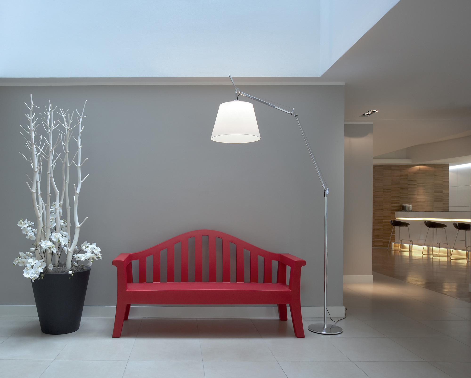 Artemide Tolomeo Mega LED Stehleuchte mit Dimmer neben roter Bank und Dekoration.