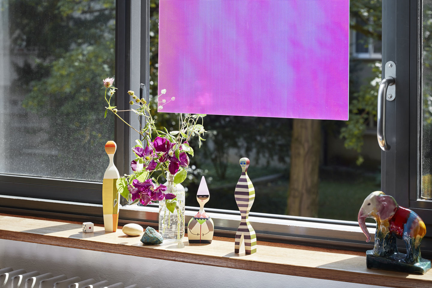 Holzfiguren von Vitra Wooden Dolls auf einer Fensterbank mit Blumen und Dekoration, blickdichtes Rollo.