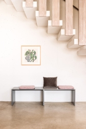 Schönbuch Add On Sitzbank in Grau mit Kissen vor weißer Wand und Treppe.
