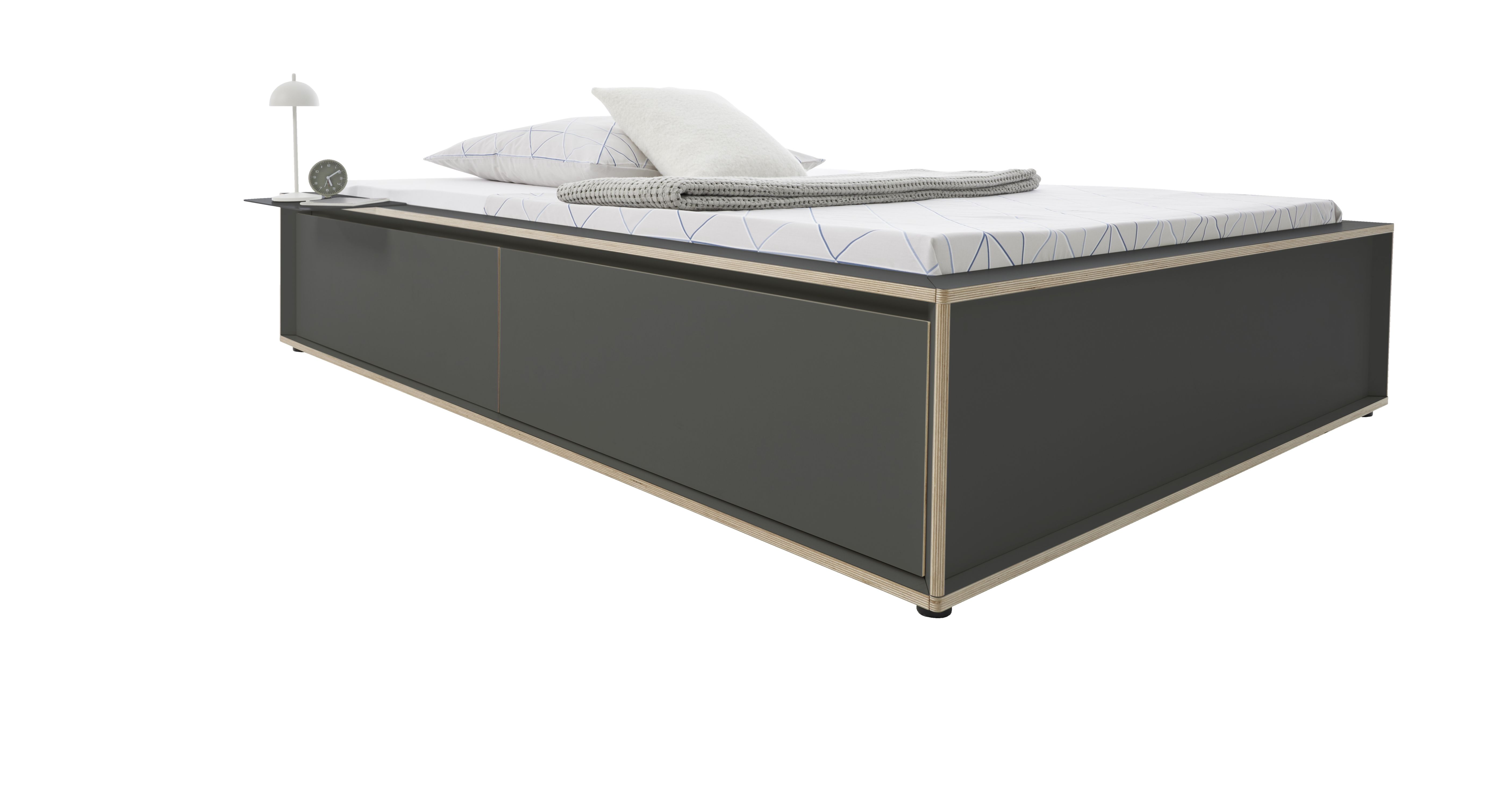 Spaze Bett von Müller Möbelwerkstätten in Grau mit Nachttisch, Lampe, Kissen und Decke.