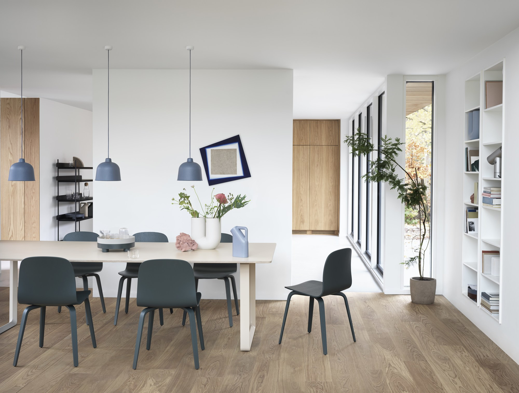 Esszimmer mit drei blauen Grain Pendelleuchten von Muuto über einem Esstisch.