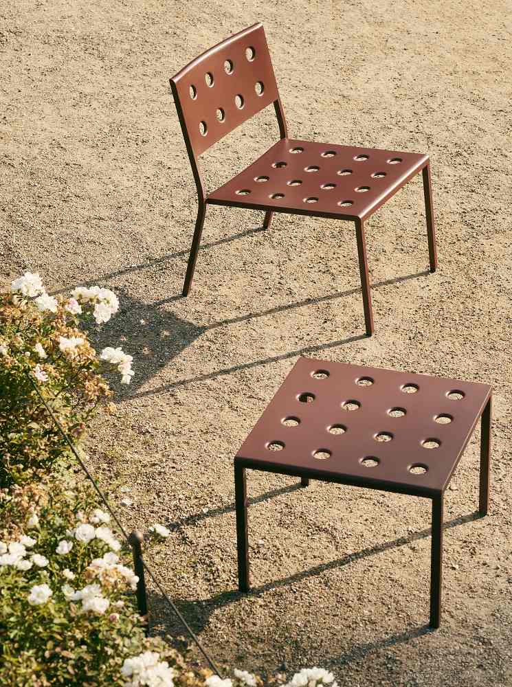 Hay Balcony Lounge Chair und Beistelltisch in Braun mit Löchern auf Kiesboden.
