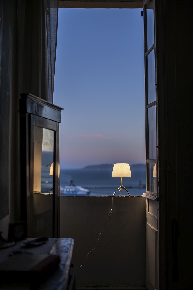 Lumiere Tischleuchte von Foscarini auf einem Balkon mit Blick auf das Meer bei Dämmerung.