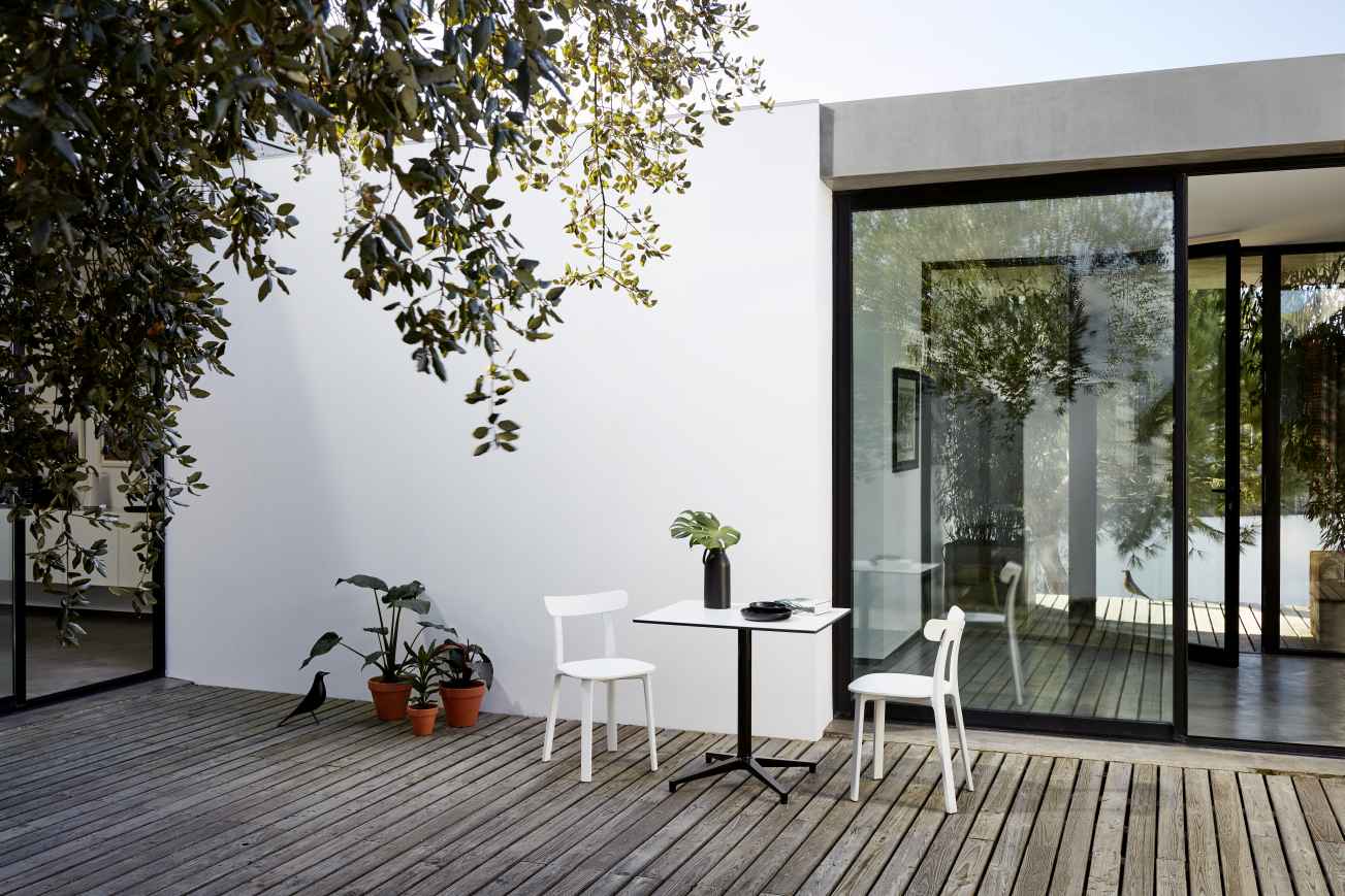 Rechteckiger Vitra Bistro Table Outdoor mit zwei Stühlen auf einer Holzterrasse.