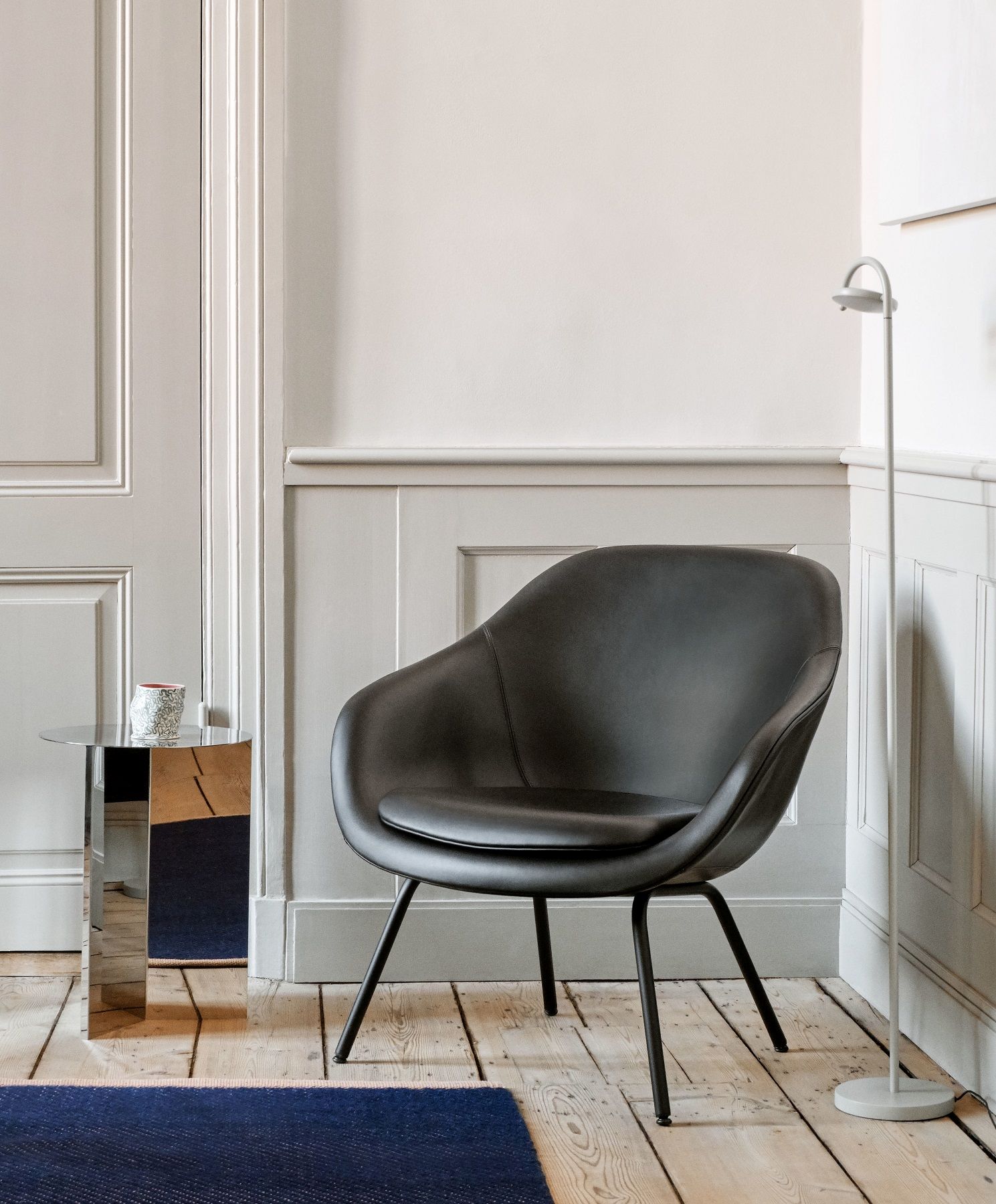 Schwarzer About a Lounge AAL 87 Sessel von Hay im minimalistischen Interieur mit Beistelltisch und Lampe.
