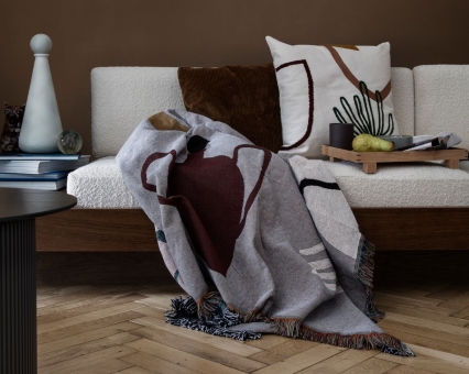 Gemusterte Tagesdecke aus Baumwolle mit Fransen auf Sofa, dekoratives Wohnaccessoire für gemütliches Ambiente.
