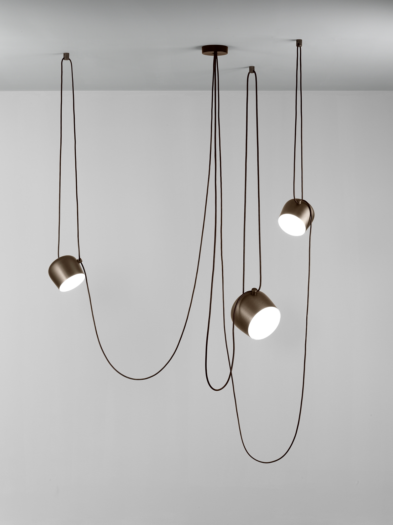 Aim Small Pendelleuchte: Drei moderne Hängelampen mit schwarzen Kabeln und weißem Licht. Flos Designleuchte.