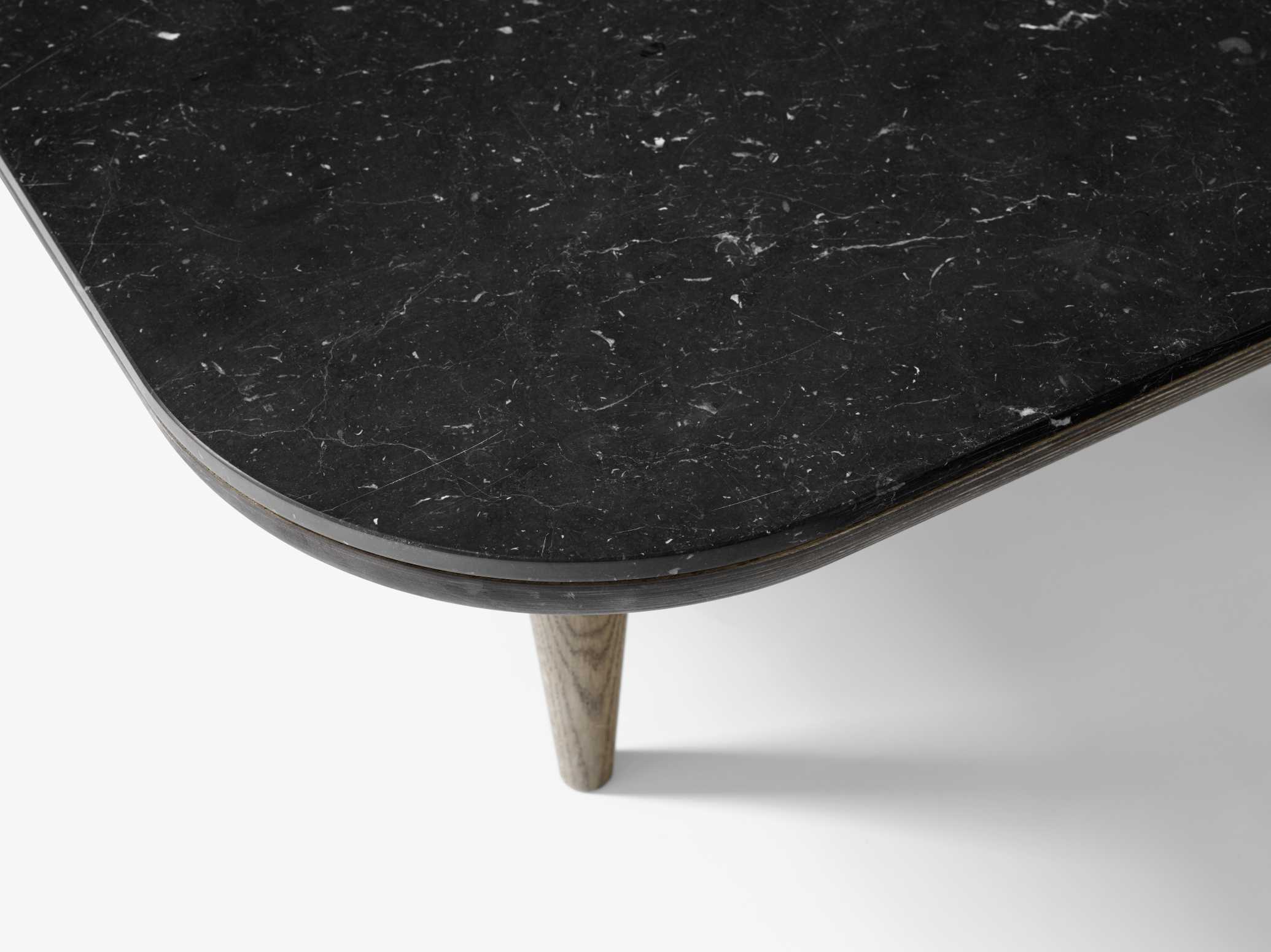 Detailaufnahme des AndTradition Fly Table Couchtischs mit schwarzer Marmorplatte und Holzbeinen.