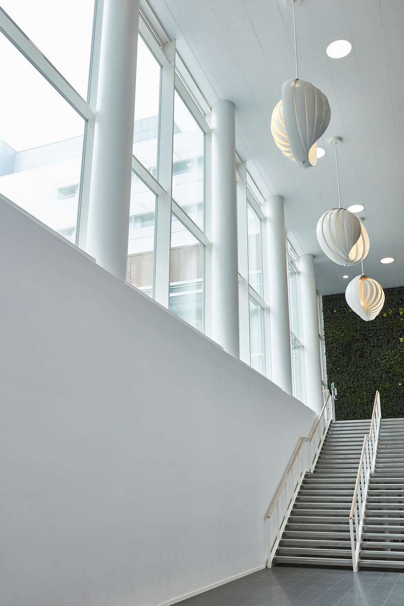 Helle Halle mit Treppe und drei weißen Verpan Moon Pendelleuchten im Vordergrund.