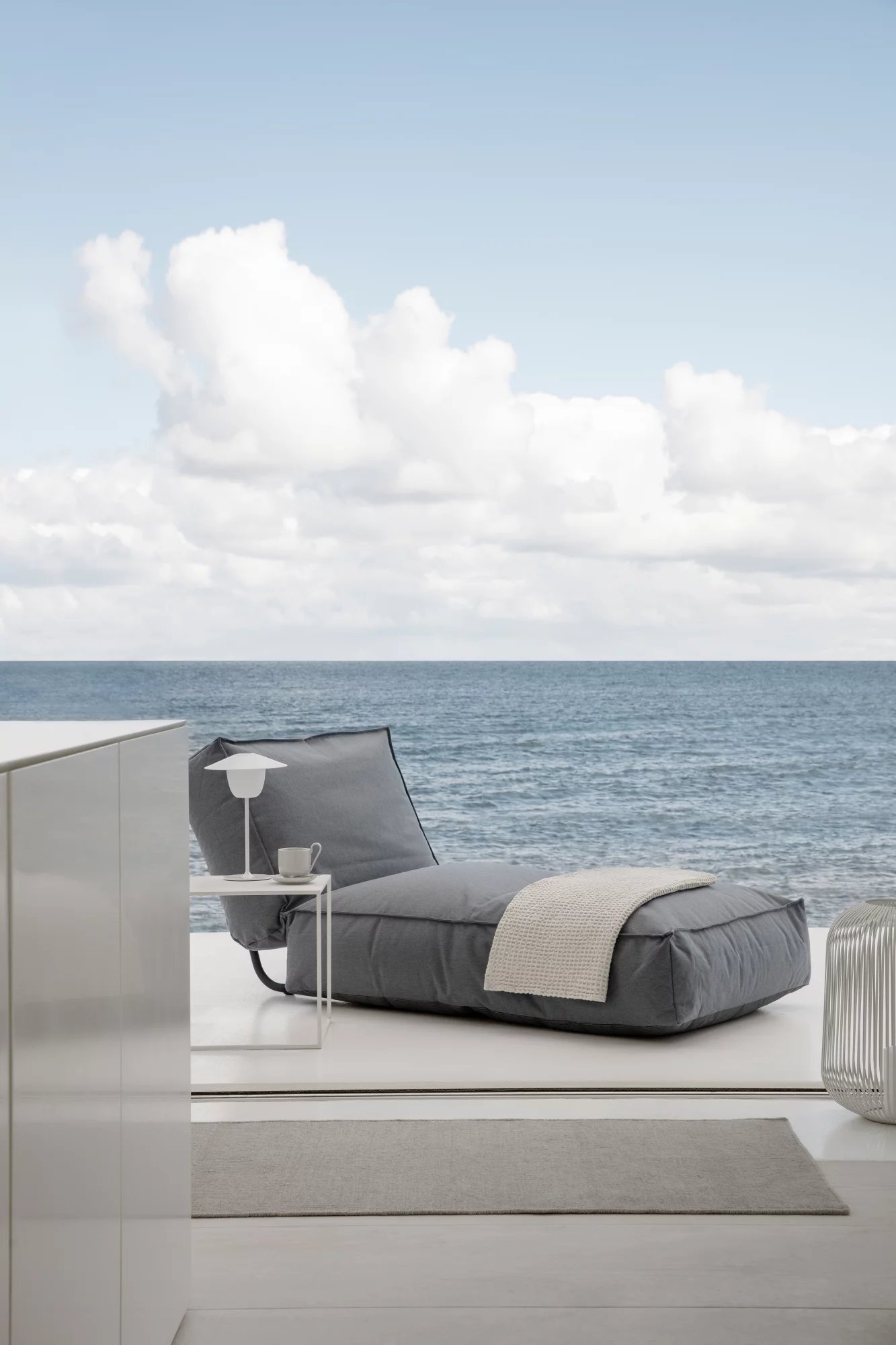 Graues Blomus Stay Bed Tagesbett mit Decke und Meerblick, ideal für entspannte Stunden.