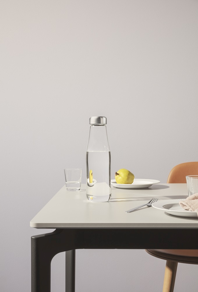 Glas Karaffe mit Deckel auf Tisch, gefüllt mit Wasser und Zitronenscheibe. Eva Solo Stil.